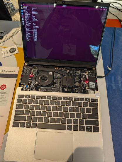 A photo of framework 13 laptop with RISC-V motherboard. The top part with a keyboard is unscrewed and motherboard with fan, heat pipes and wifi adapters are visible.