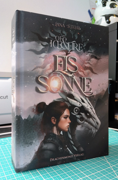 Foto eines Buches mit einer jungen Frau und einem mechanischen Drachen im Profil als Cover