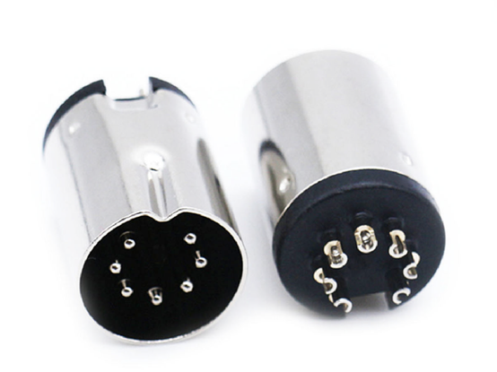 Photograph of a minimal 7 pin big DIN connector showing it from the front and back ends. The seven pins are arranged in a nearly completely circular layout.