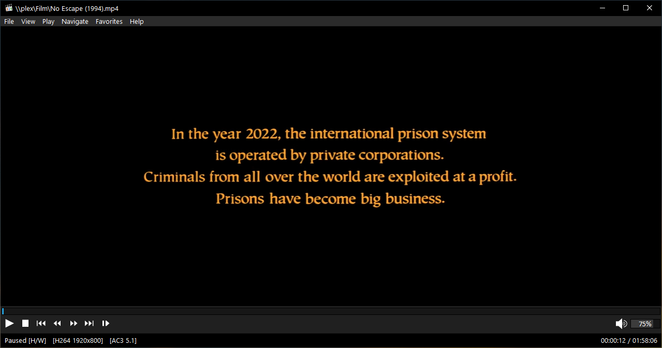 Still image. Screenshot of Media Player Classic playing No Escape (1994).
Orange text on black background reads:
In the year 2022, the international prison system is operated by private corporations. Criminals from all over the world are exploited at a profit. Prisons have become big business.