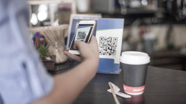 Eine Hand hält ein Smartphone und scannt einen QR-Code ab (Foto: IMAGO, Westend61)