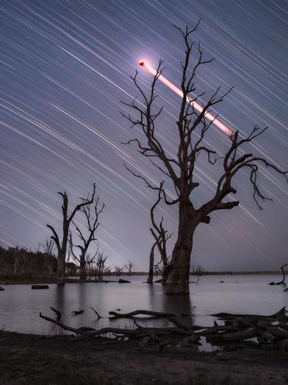 Composite long exposure showing star trails and the Moon moving into a total eclipse.