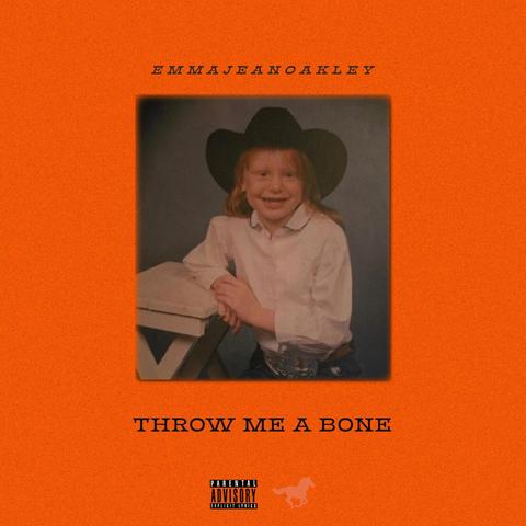 Black text on an orange background. Text on top reads Emma Jean Oakley in one word. Text on bottom read Throw Me a Bone. Photo in the center shows a four-year-old girl grinning into the camera. She is wearing a black cowboy hat.