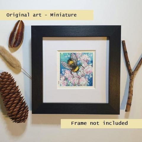A tiny artwork of a bee sitting on pink flowers with a blue background.
An original art work, please note that the frame is not included.
Watercolour and mixed media on white acid free artist watercolour paper.
Approximately 7.5 x 7.5cm, will fit a 3 x 3 inch photo frame.