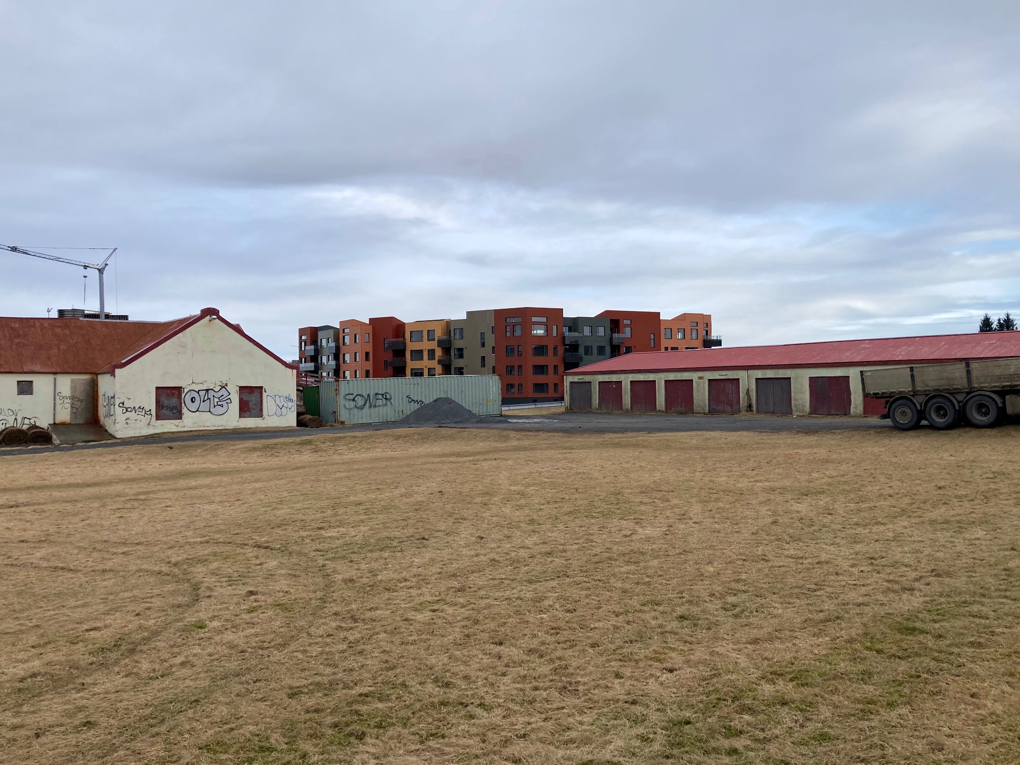 An old run-down barn and some old run-down garages with a new building in between them.