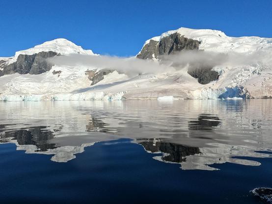 Two mountains and a cloud with a reflection in the water