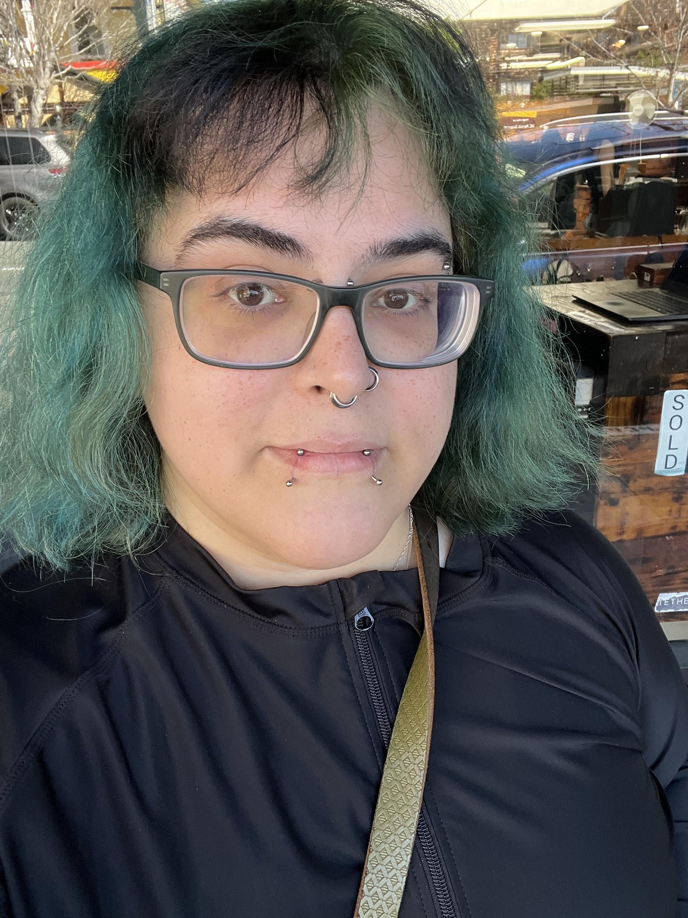 Green haired person with fresh vertical labret piercings on the bottom lip