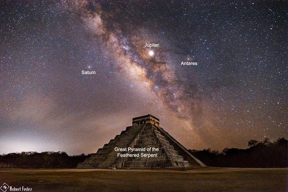 Milky Way and other astronomical objects photographed behind a pyramid.