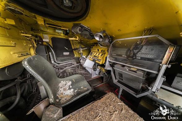 Interior of an OT-64 SKOT armoured personnel carrier with yellow walls, multiple control panels, and two seats.