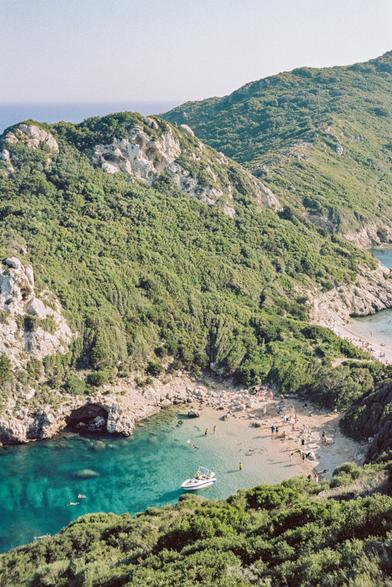 Porto Timoni is one of the most beautiful places in Corfu. It is a cape with a double beach with turquoise water and light sand. Many hills covered with greenery and trees, the sky is clear and cloudless, the sun is shining.