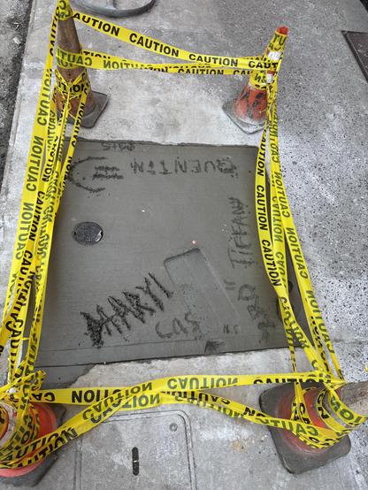 Yellow police tape protect a square of fresh concrete. A new addition is seen in one corner.