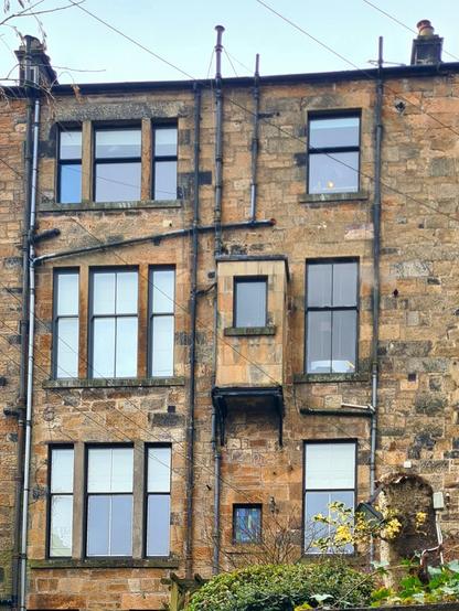 A small box-like extension projecting from the 2nd floor of a traditional sandstone Victorian building in Glasgow.