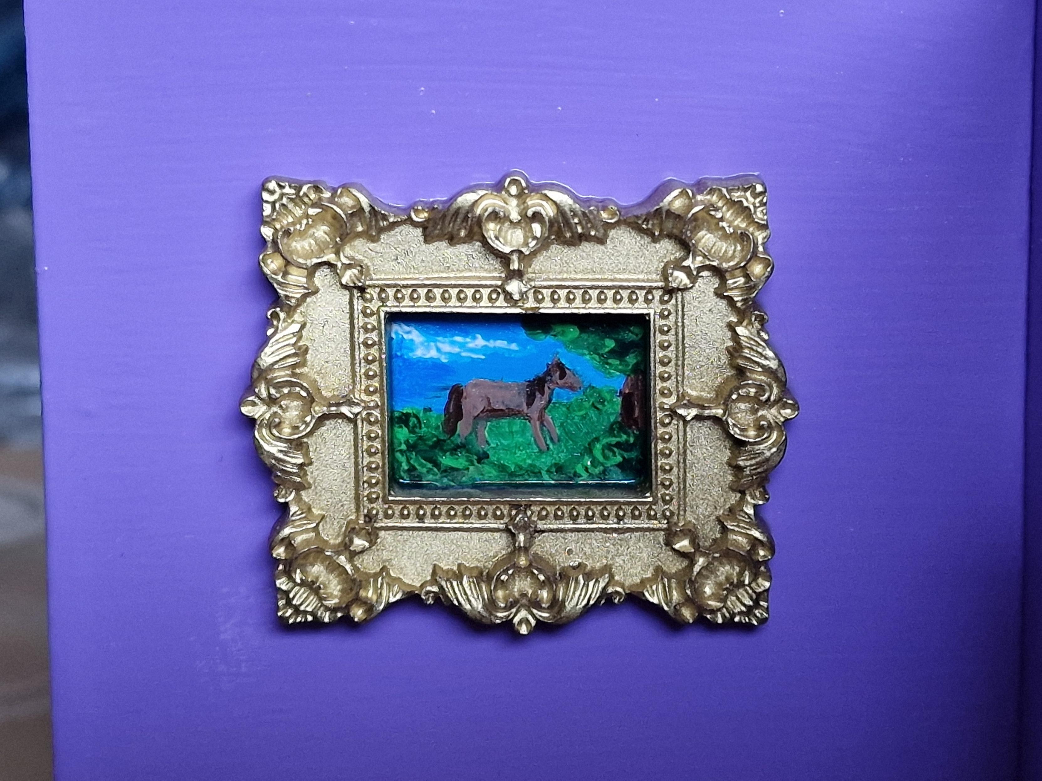 Very tiny painting of a brown horse in a field in a gold frame