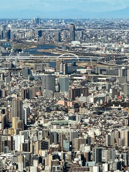 View from the top of an observation tower overlooking dense urban development including thousands of buildings, bridges, rail lines, etc.