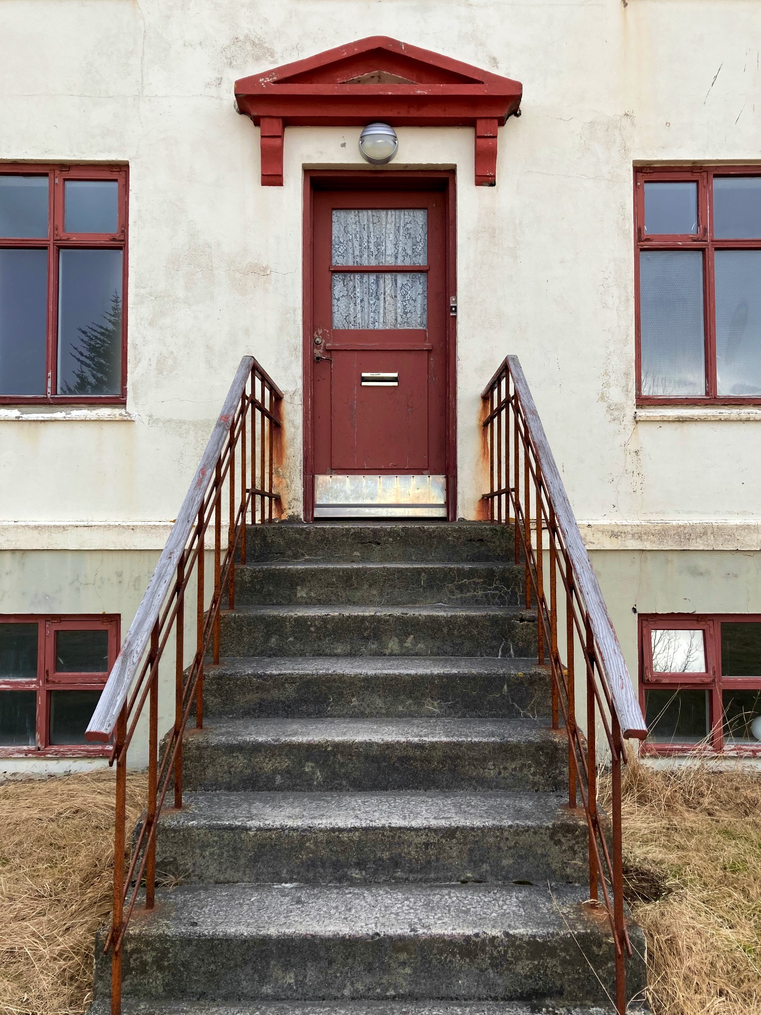 Stairs with a rusty railing leading to a red door