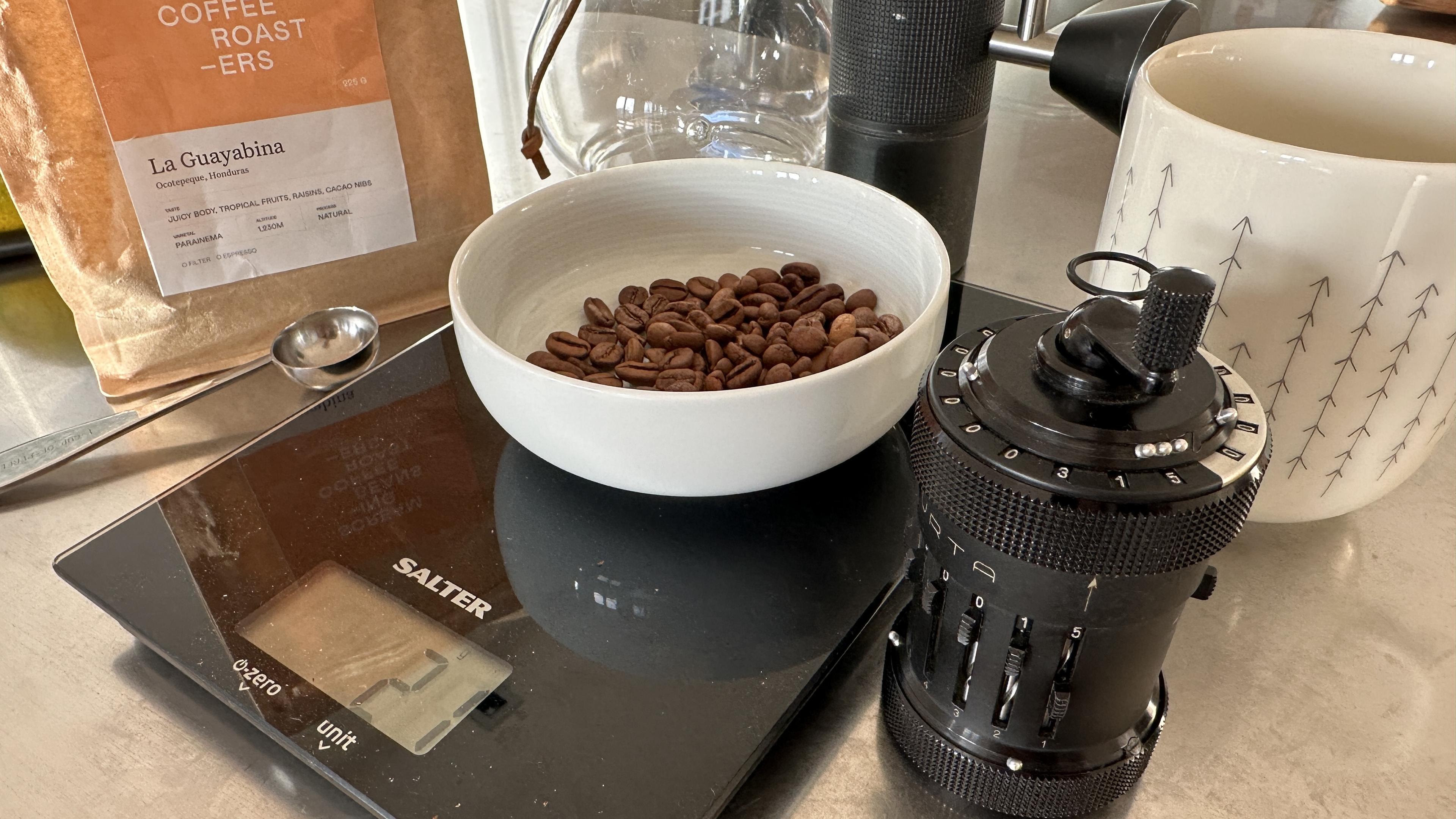 Curta mechanical calculator (which looks like a coffee grinder) next to a bowl of coffee beans. The result in the text can be read from the top of the machine.