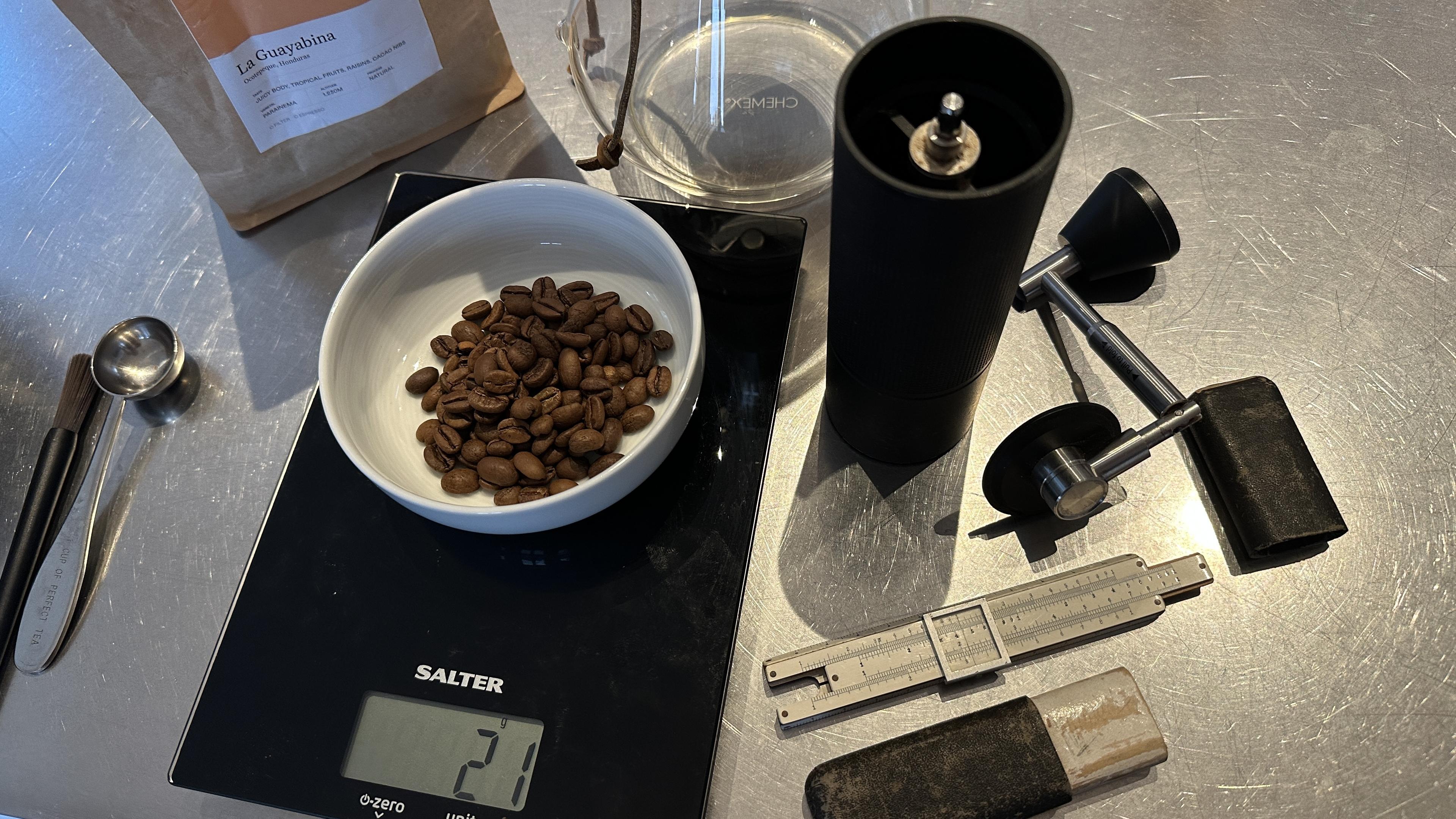 Coffee making setup with a scale, grinder, 21g of beans and a tiny sliderule