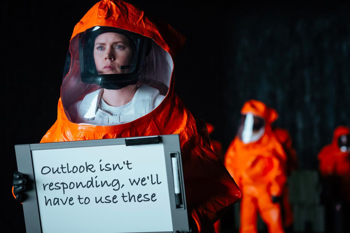Scene from the movie "Arrival" where the characters are inside the alien spaceship wearing hazmat suits. Amy Adams' character is trying to communicate with the aliens with a whiteboard that says "Outlook isn't responding, we'll have to use these"