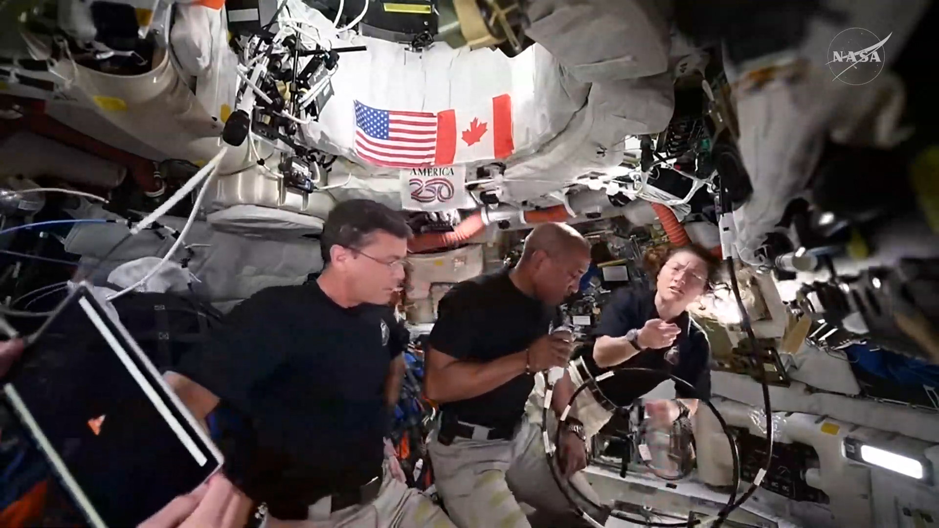 screenshot of the artemis livestream; one of the astronauts is holidng their PCD, with a VLC window open and maximized. other astronauts are talking with the ground crew. there's an US and a Canadian flag on the top of the frame