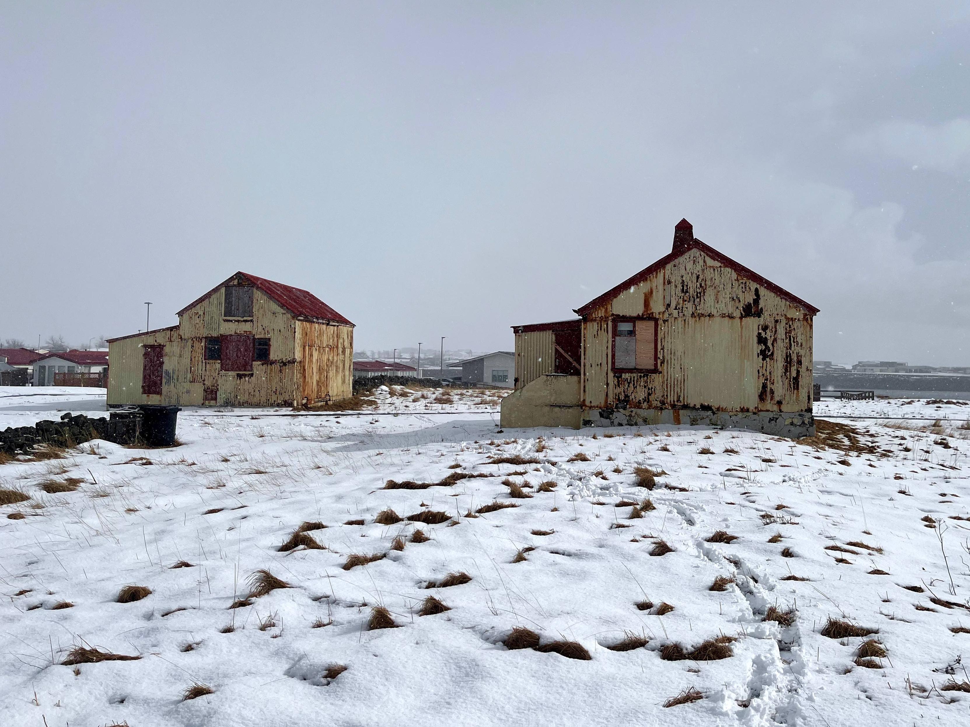 An abandoned barn and house surrounded by snow.