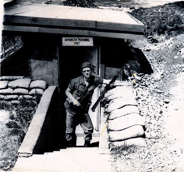 me, in jungle bunnie fatigues, holding an M-16 automatic rifle in my left hand and trying to look like a tough guy