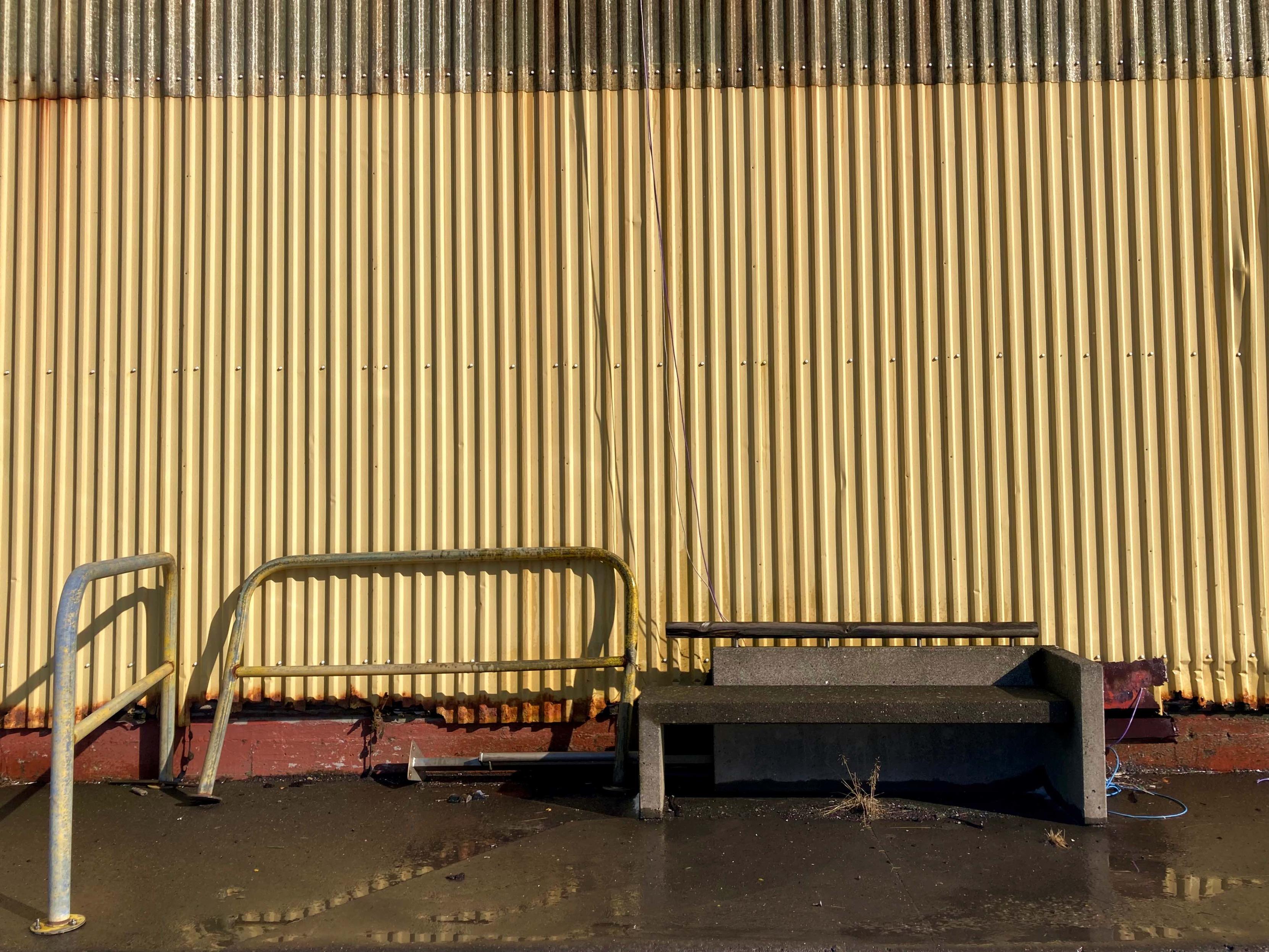 A concrete bench against a yellow wall