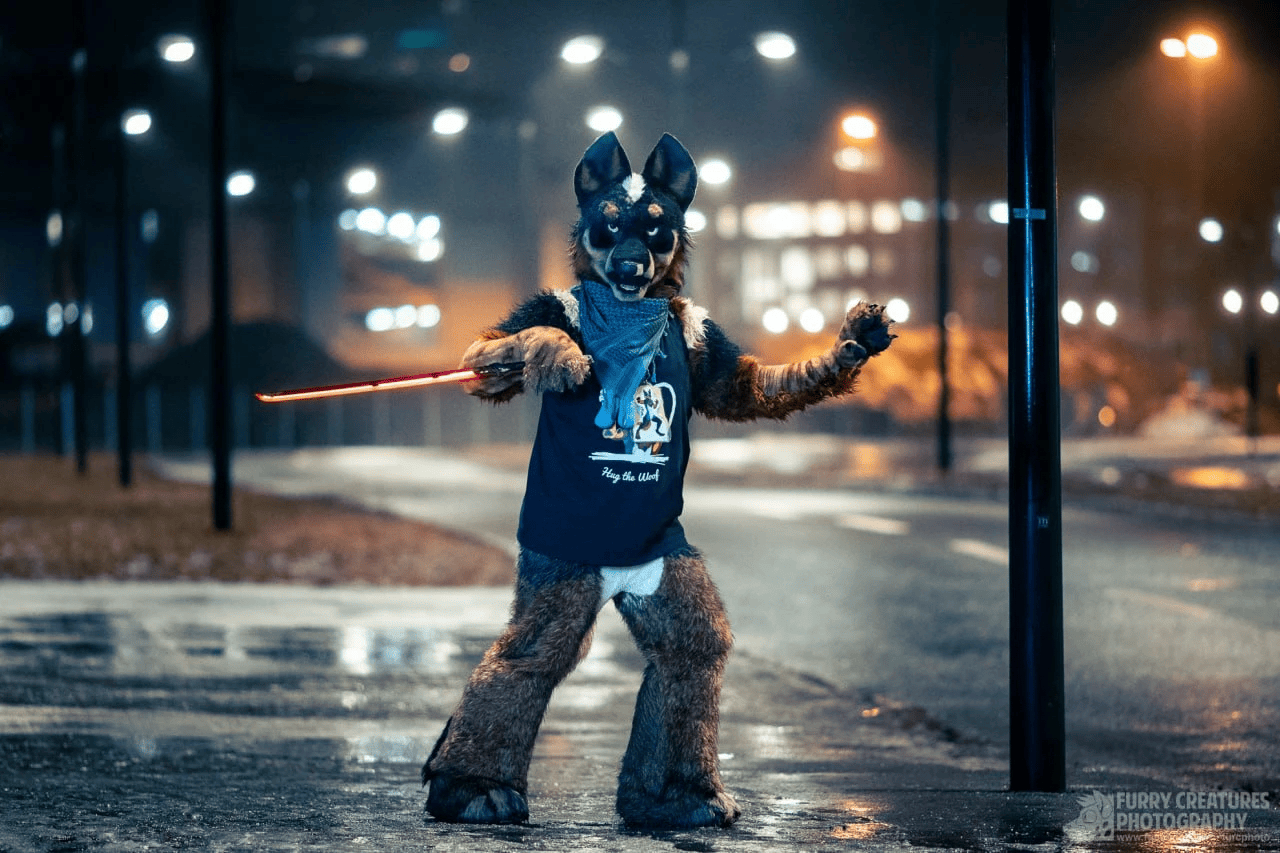 Blue Heeler fursuiter posing with a Cyberpunk katana prop, with Malmö at night in the background.