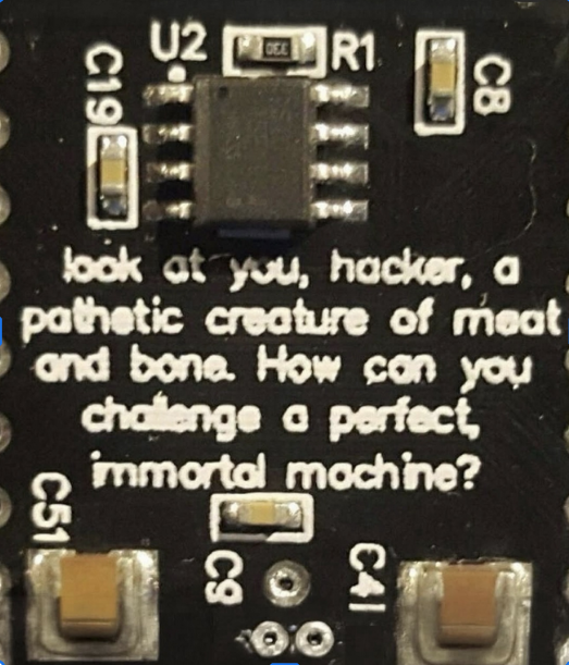 Close up of part of a circuit board, with the text "look at you, hacker, a pathetic creature of meat and bone. How can you challenge a perfect, immortal machine?"