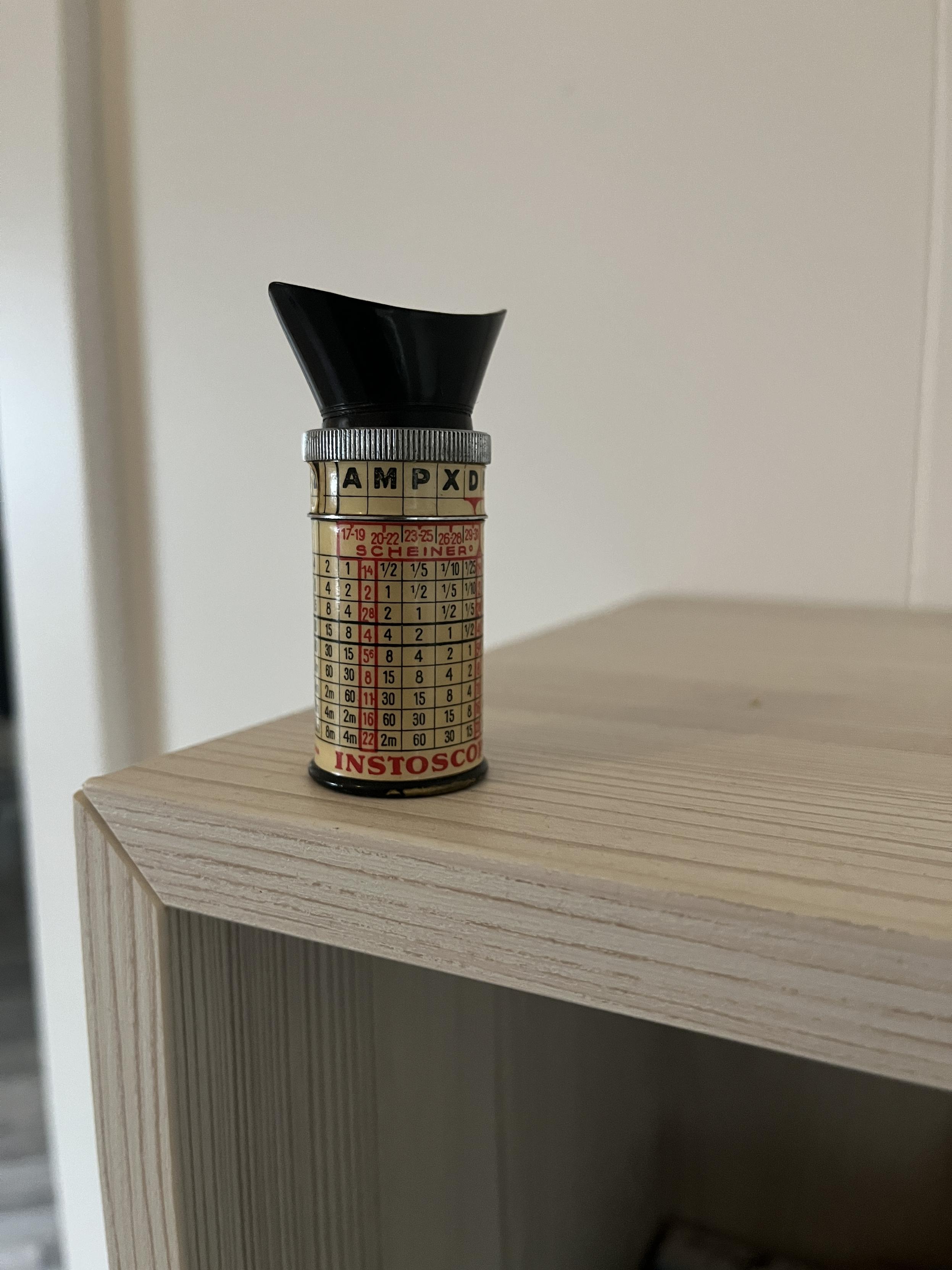 A weird cylindrical object with a viewfinder on one end and charts on its body
