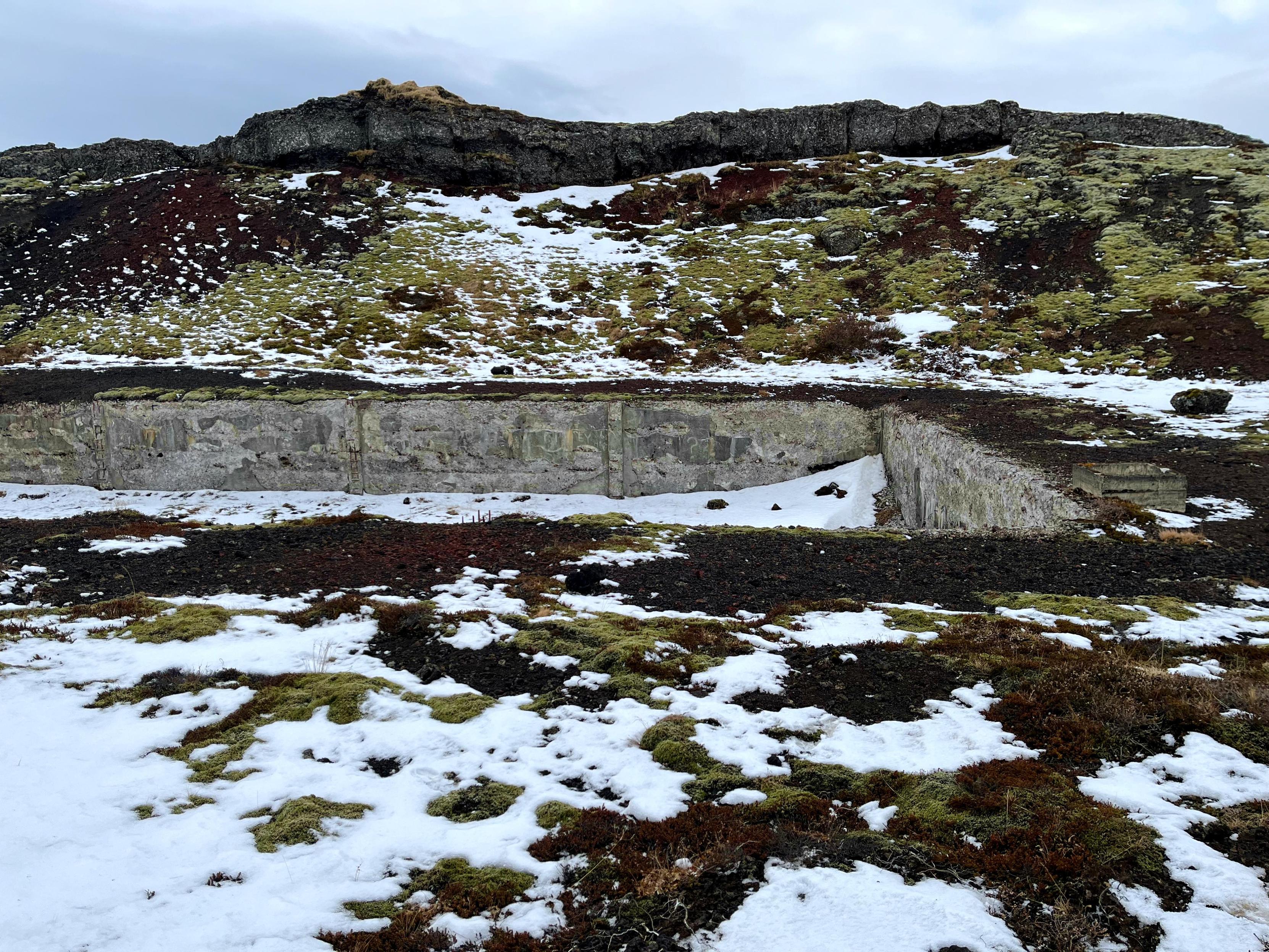What remains of a war relic surrounded by snow, moss and rocks.