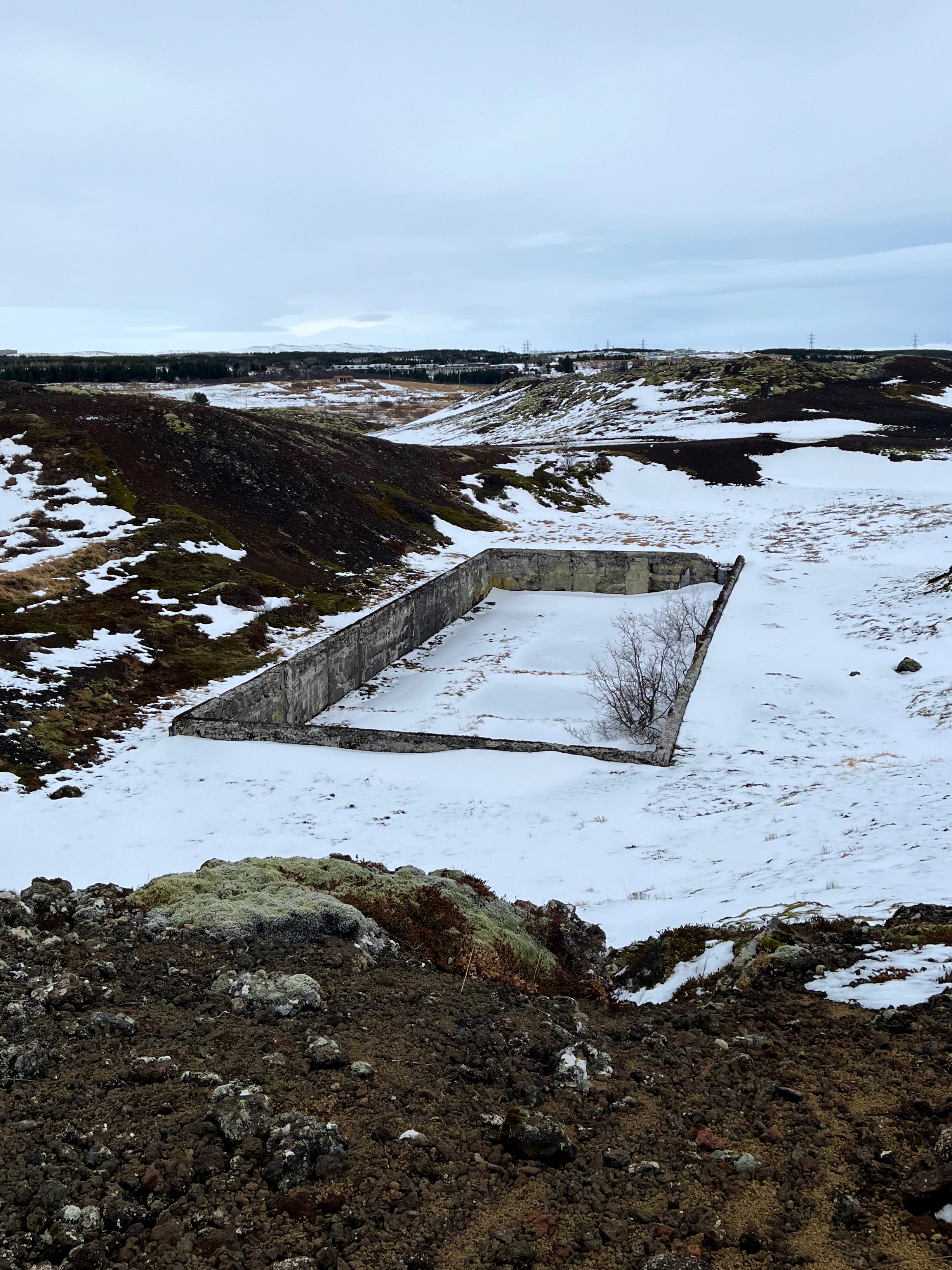 Remnants of a World War II camp surrounded by rock and snow and moss.