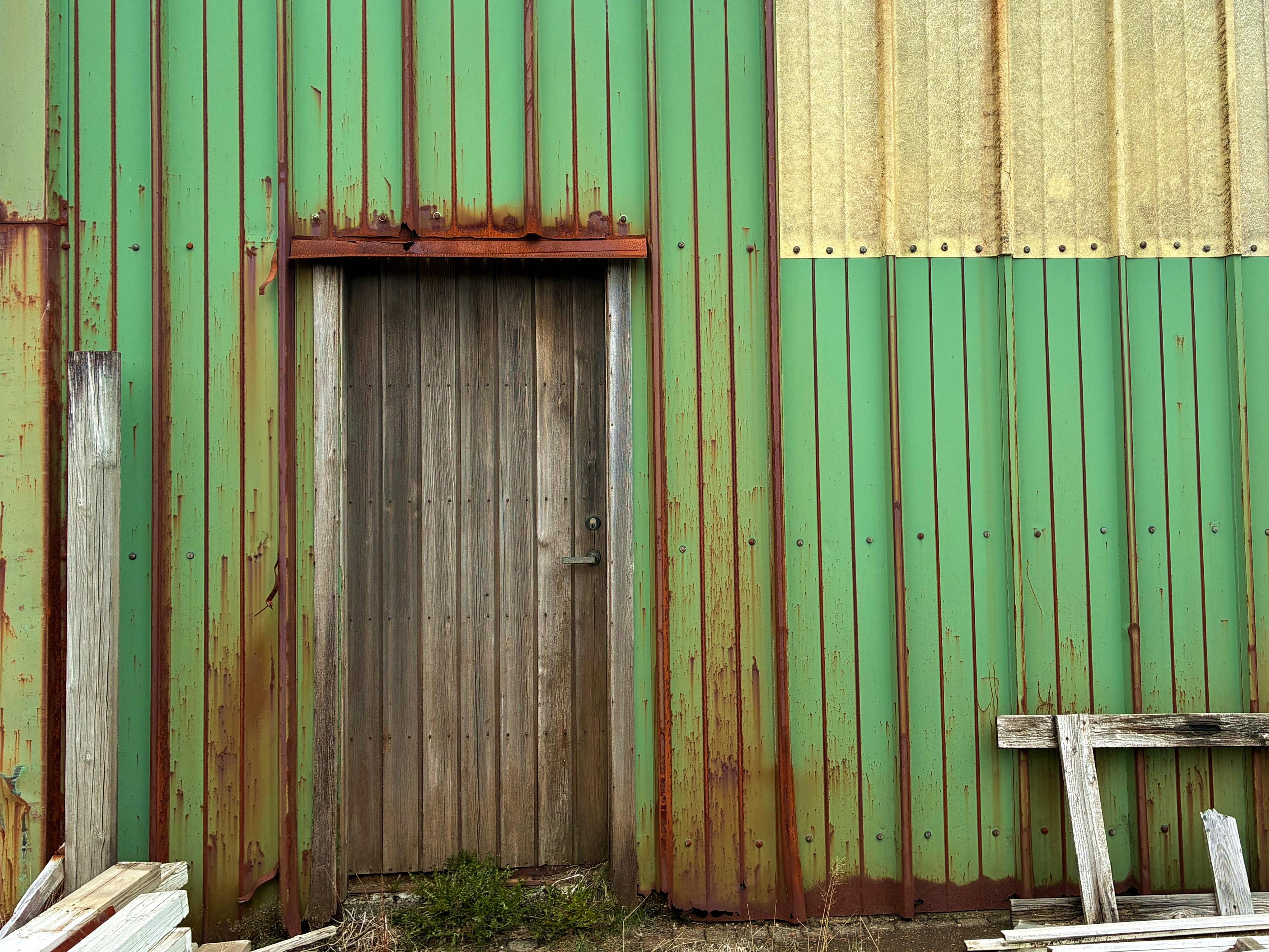 A weathered old door against a rusty green wall.