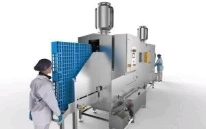 A blue plastic industrial pallet is inserted into a cleaning apparatus.
