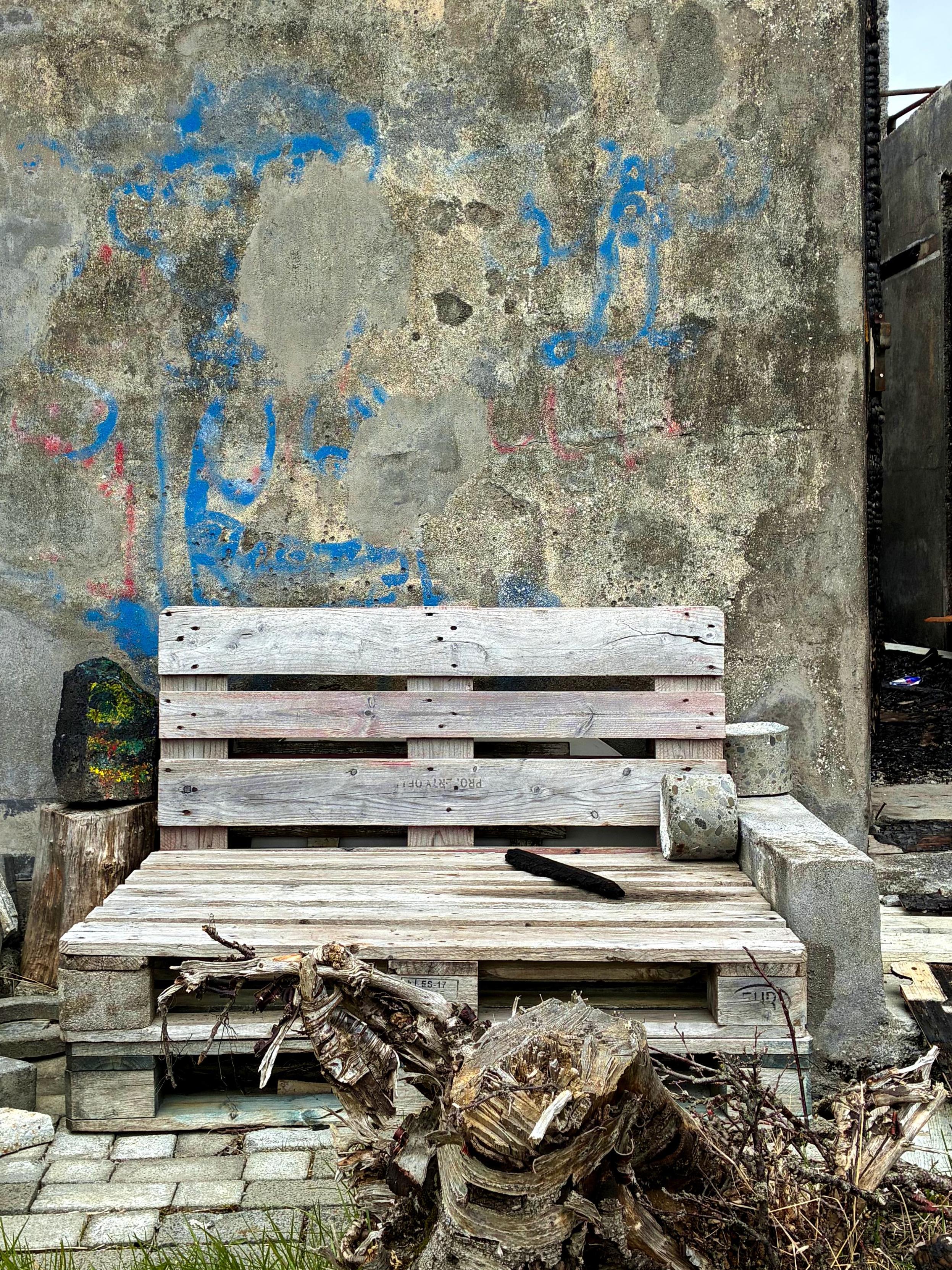 A homemade bench against a concrete wall.