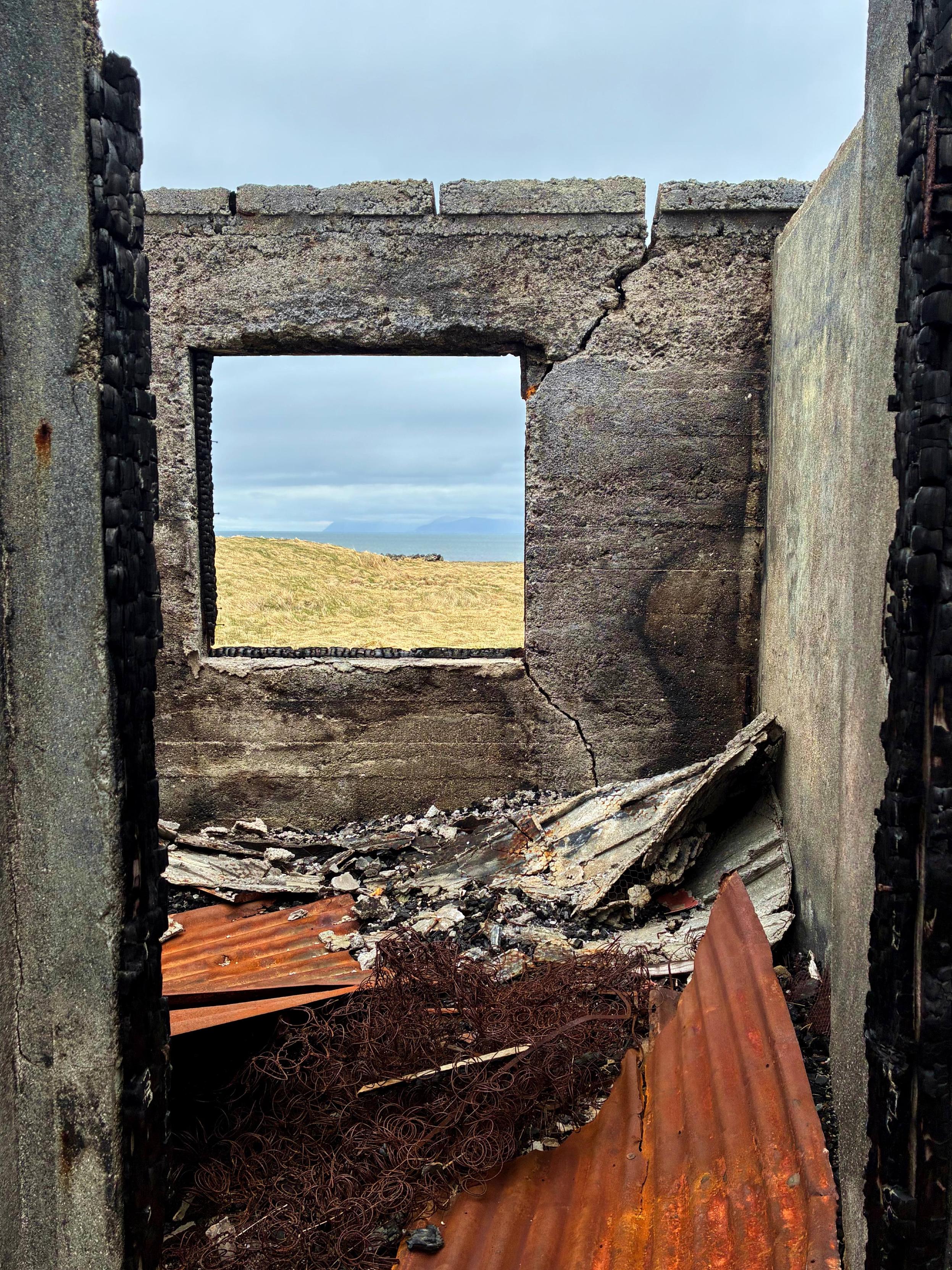 A window in an abandoned building looking out at the sea.