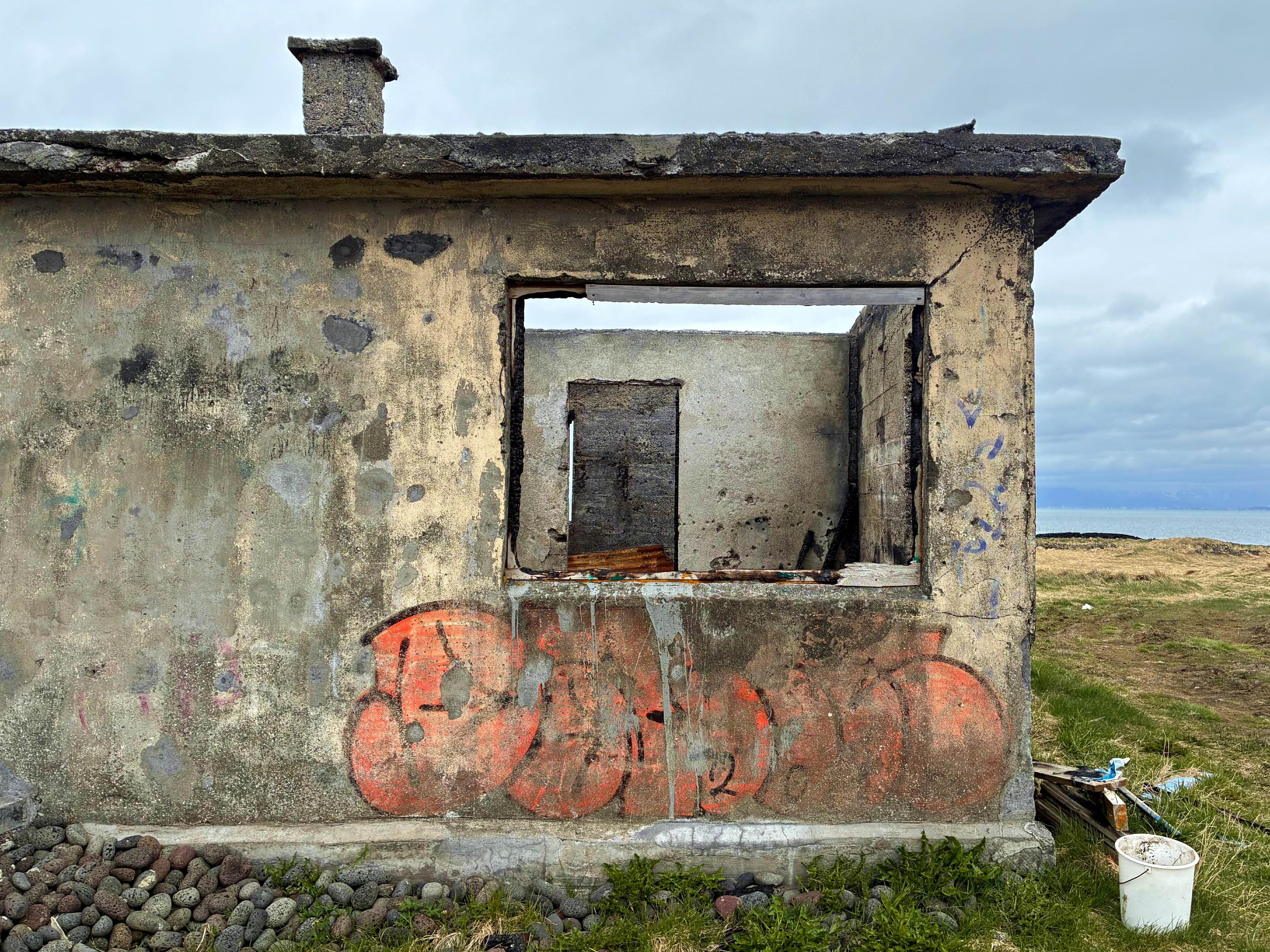 What is left of a small abandoned house with the sea in the background.