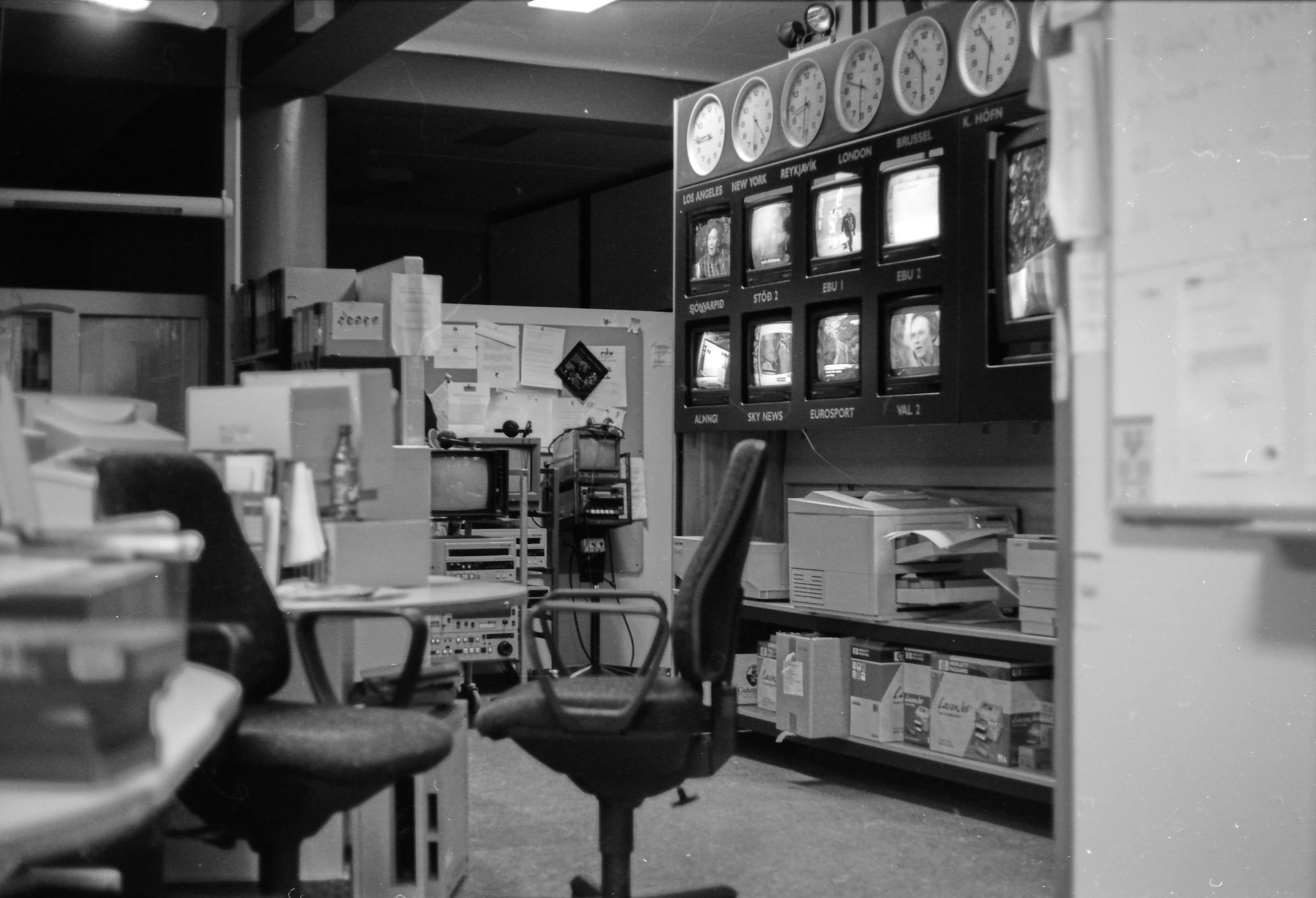 A photo from an old-style newsroom showing a number of screens with various broadcasts and clocks showing various time zones.
