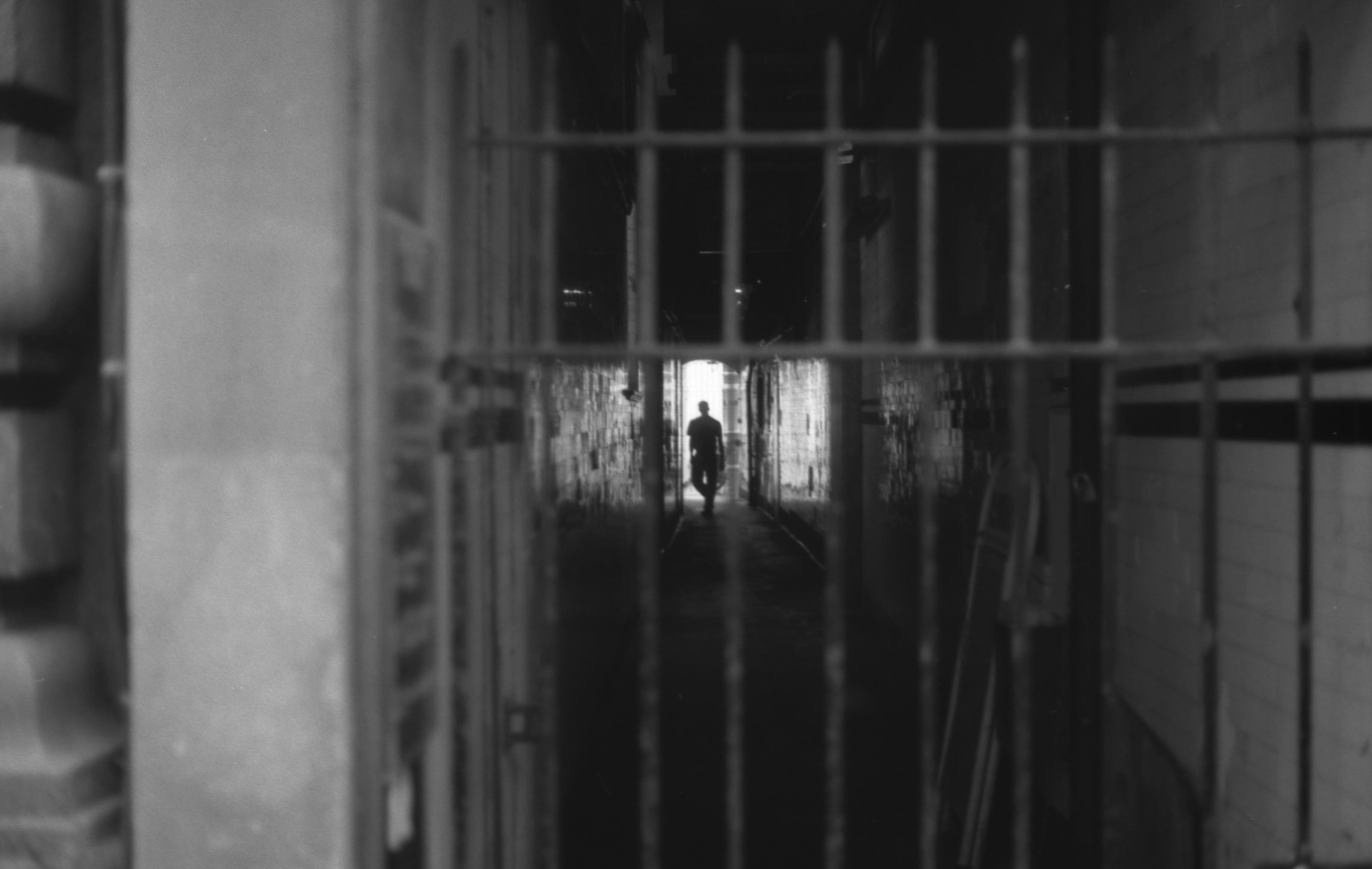 Through a gate, down a hall, we see a silhouette of a man.