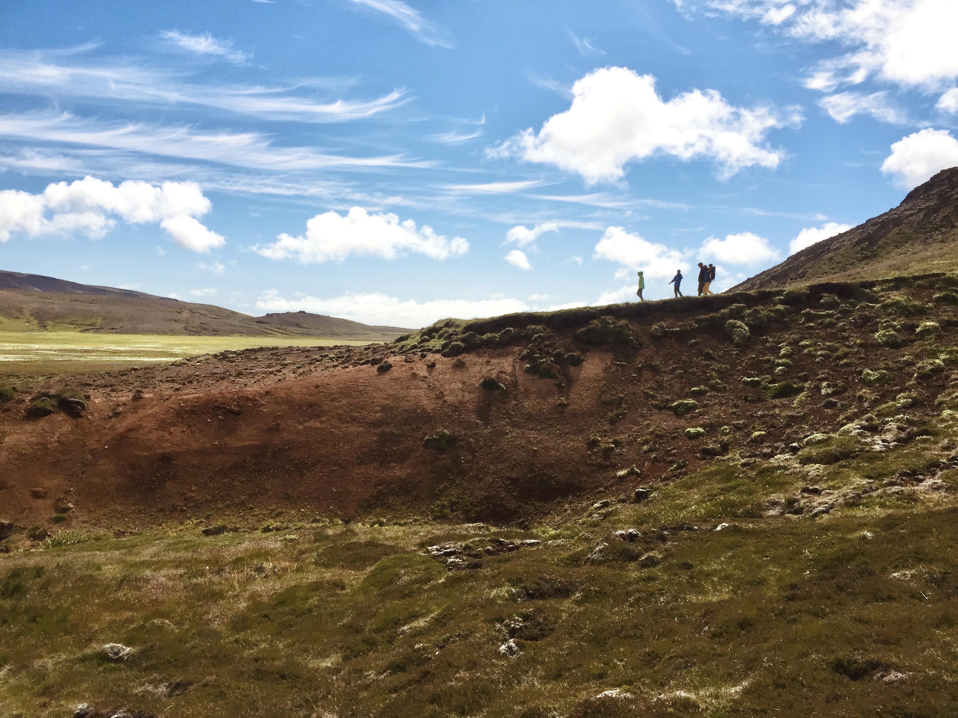 Tourists walk along a hill in a geothermal area somewhere in Reykjanes IIRC