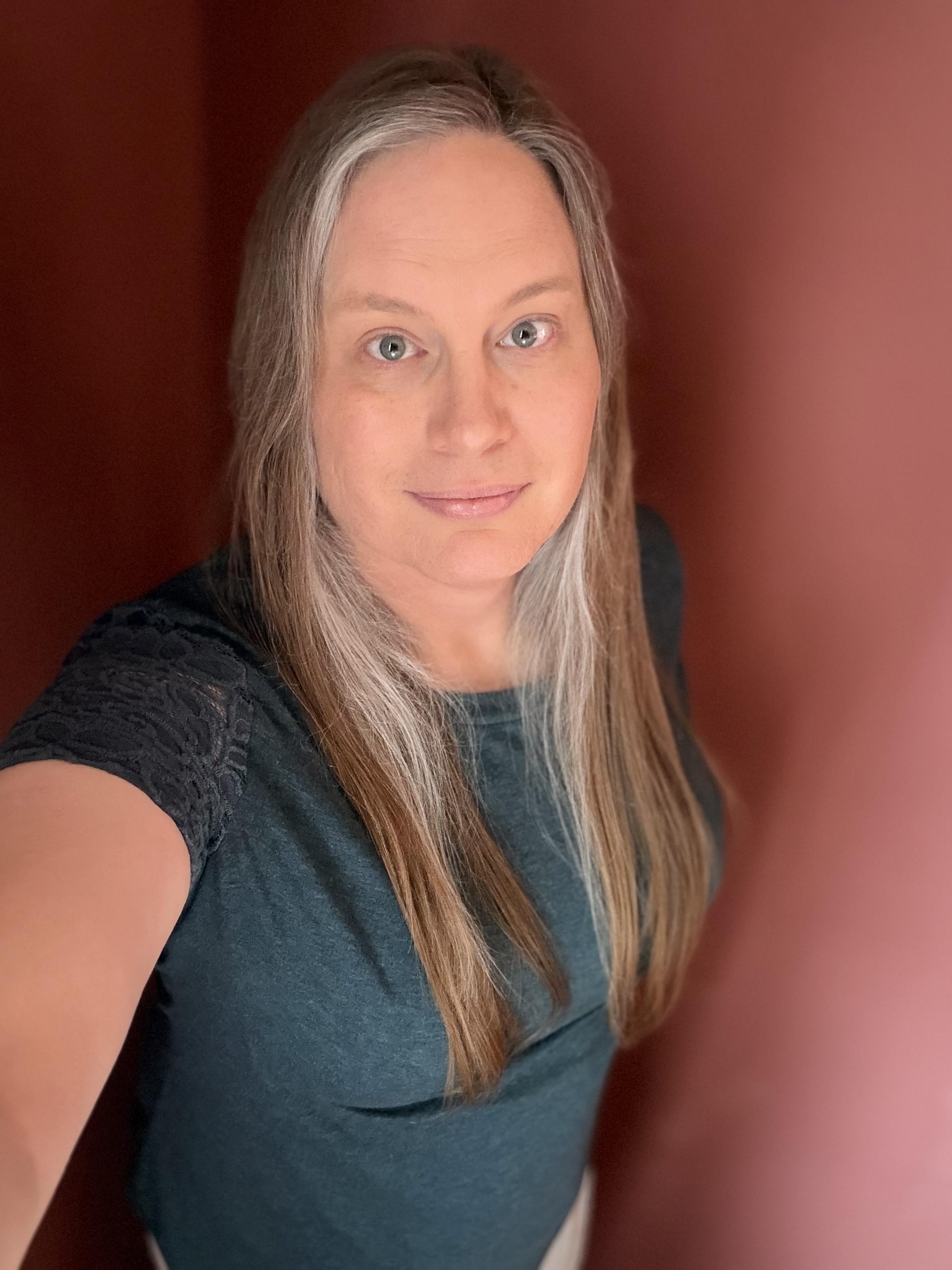 Nice selfie of a white woman with long hair and a turquoise shirt.