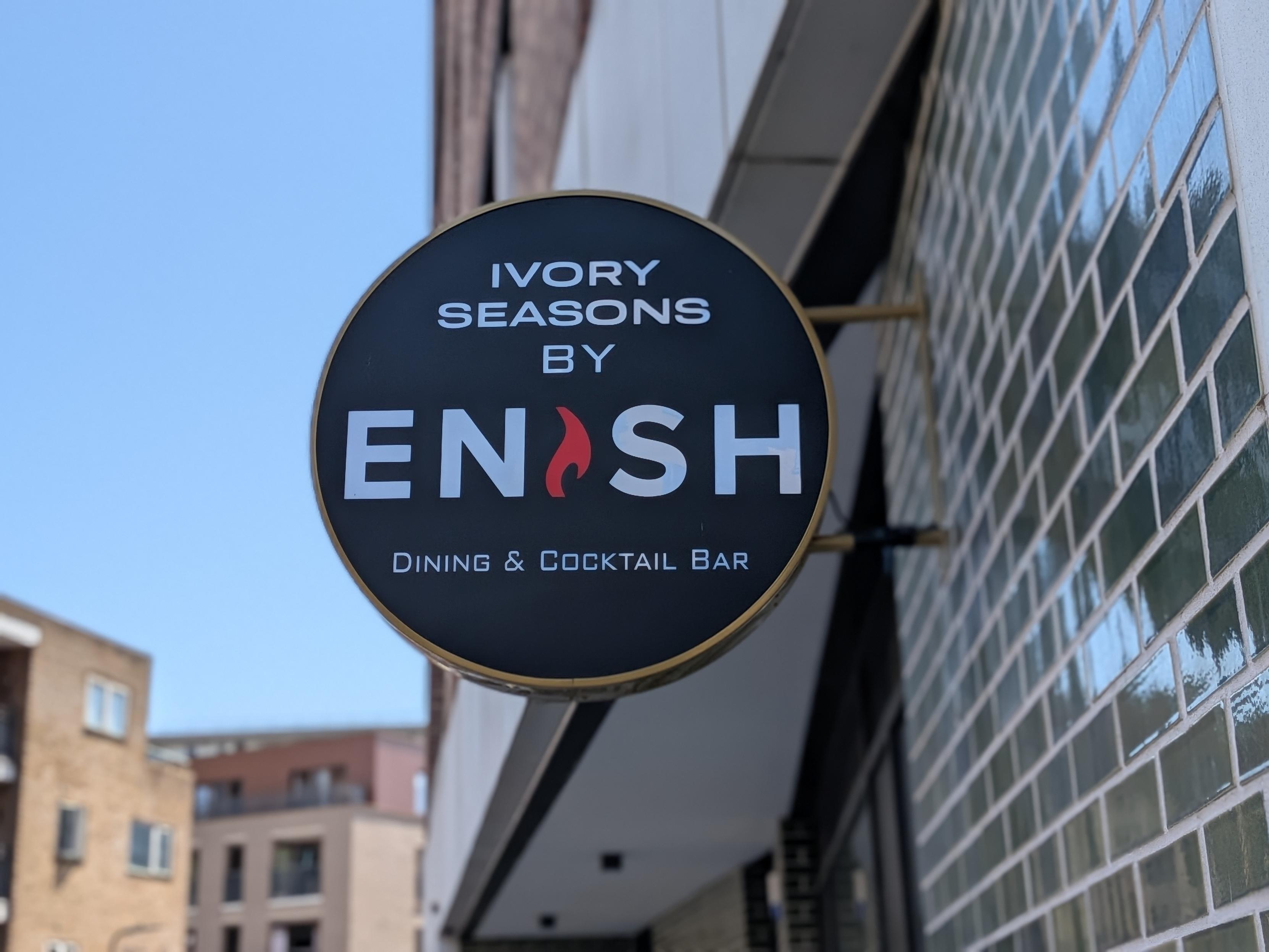 A round sign protruding from a tiled wall reading ENSH