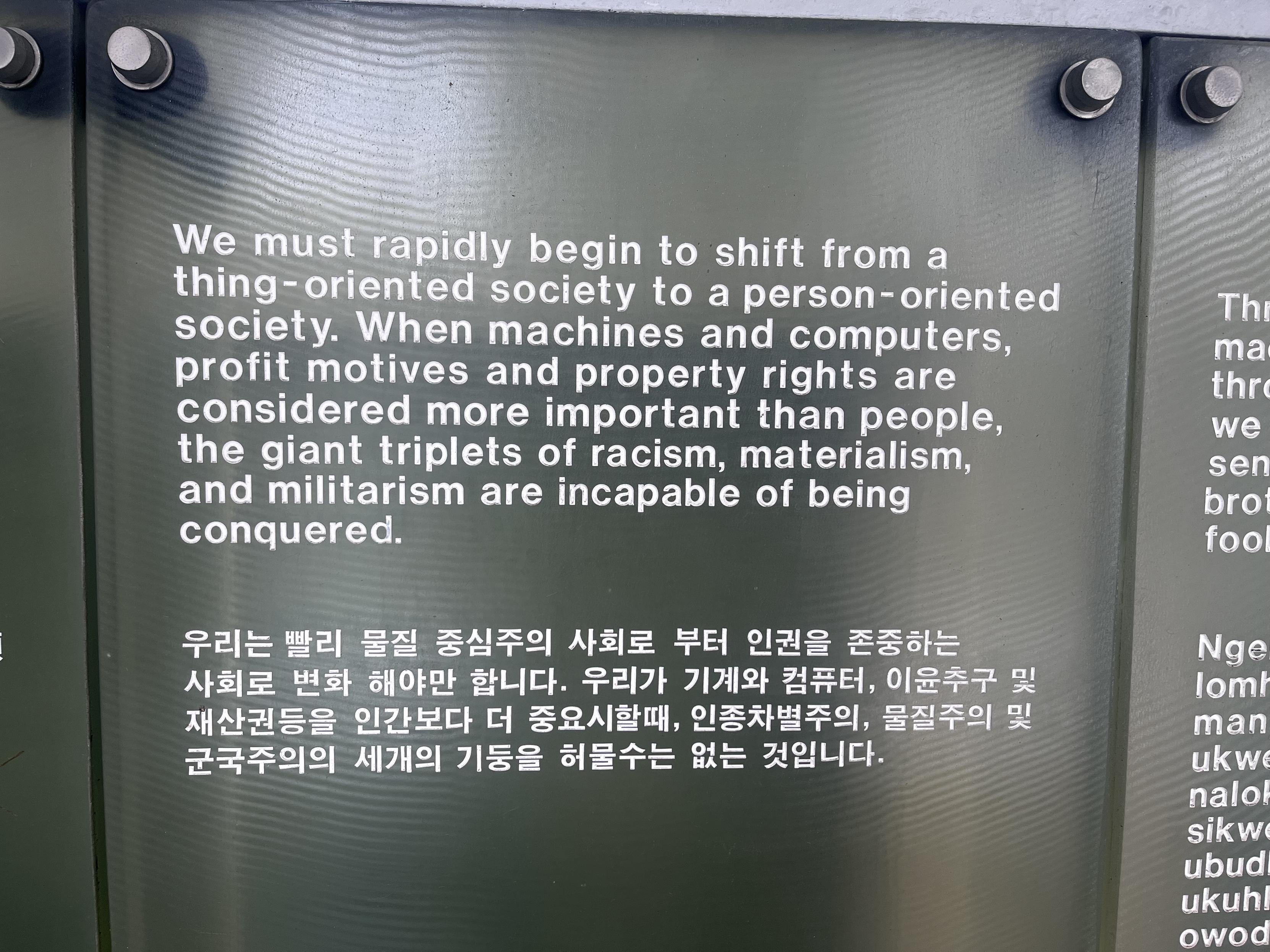A plaque which reads “We must rapidly begin to shift from a thing-oriented society to a person-oriented society. When machines and computers, profit motives and property rights are considered more important than people, the giant triplets of racism, materialism, and militarism are incapable of being conquered. “ Beneath it is the text translated into Korean (I believe)