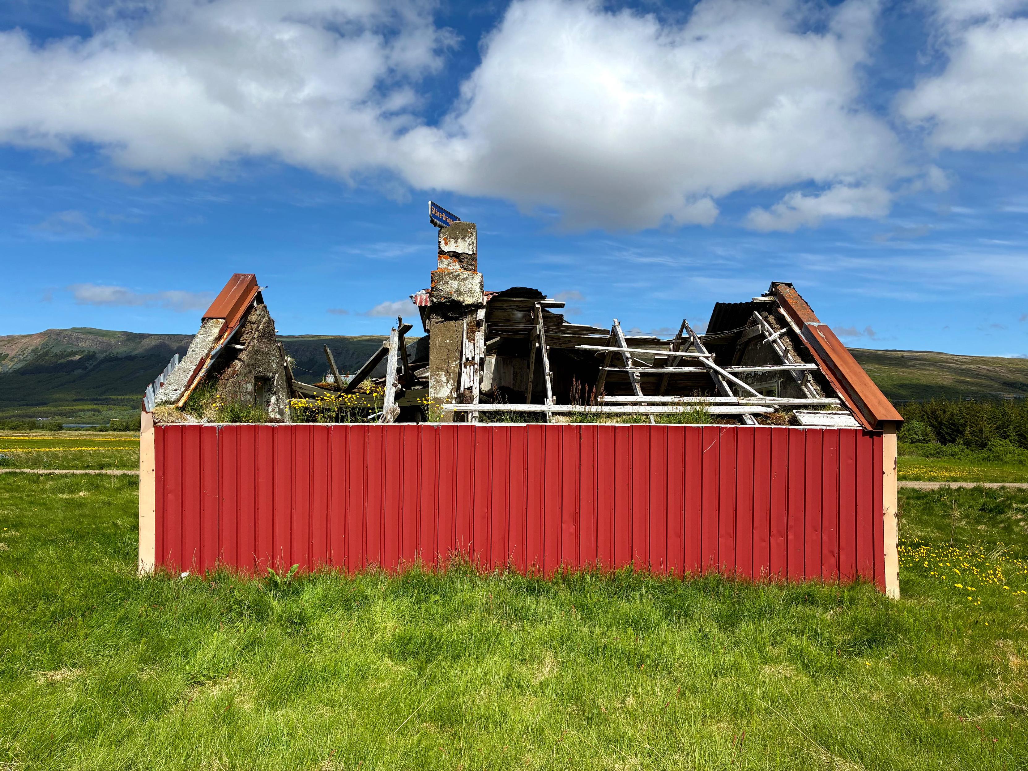 An abandoned red house with a collapsed roof.