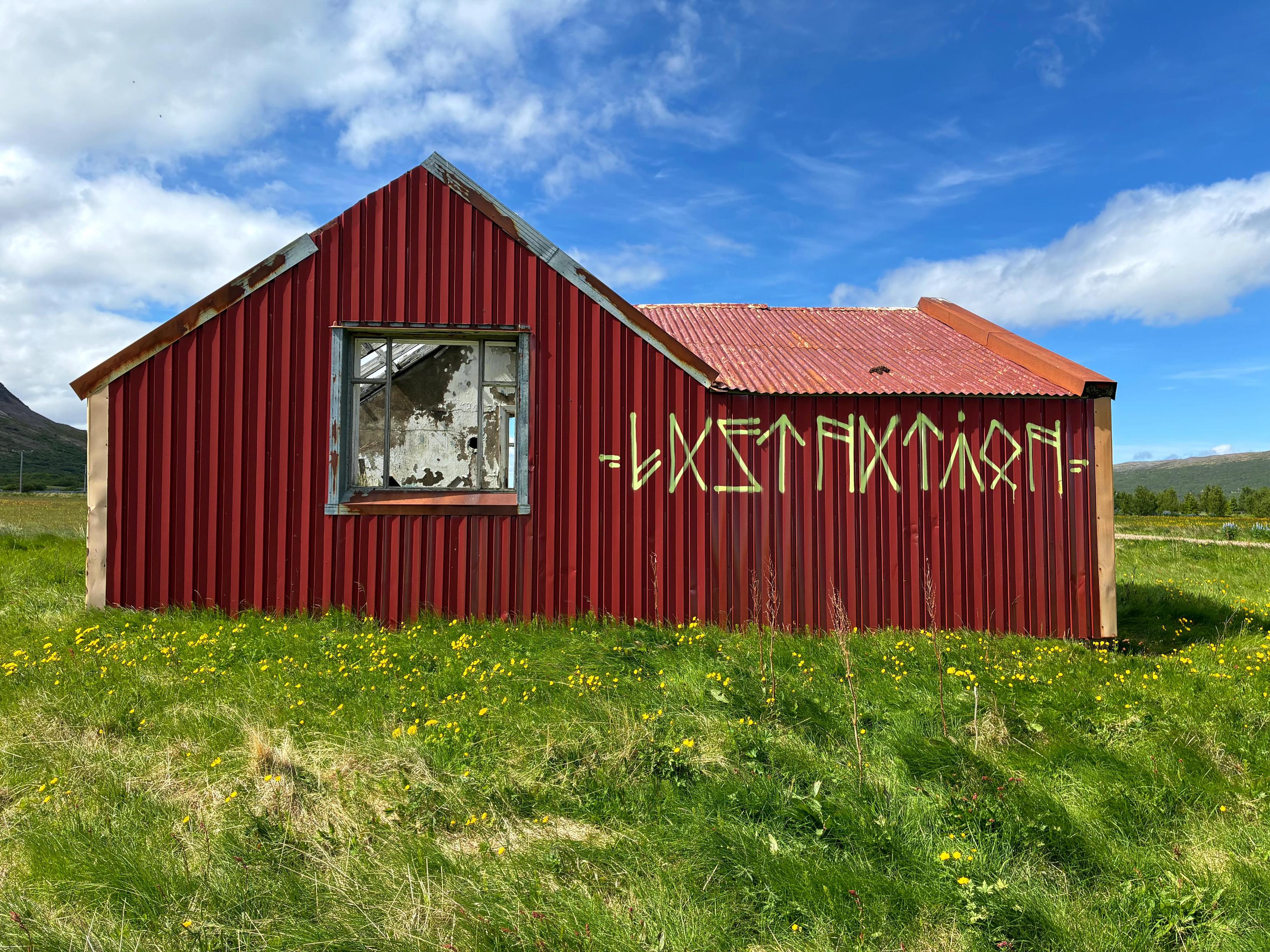 An abandoned red house surrounded by grass.