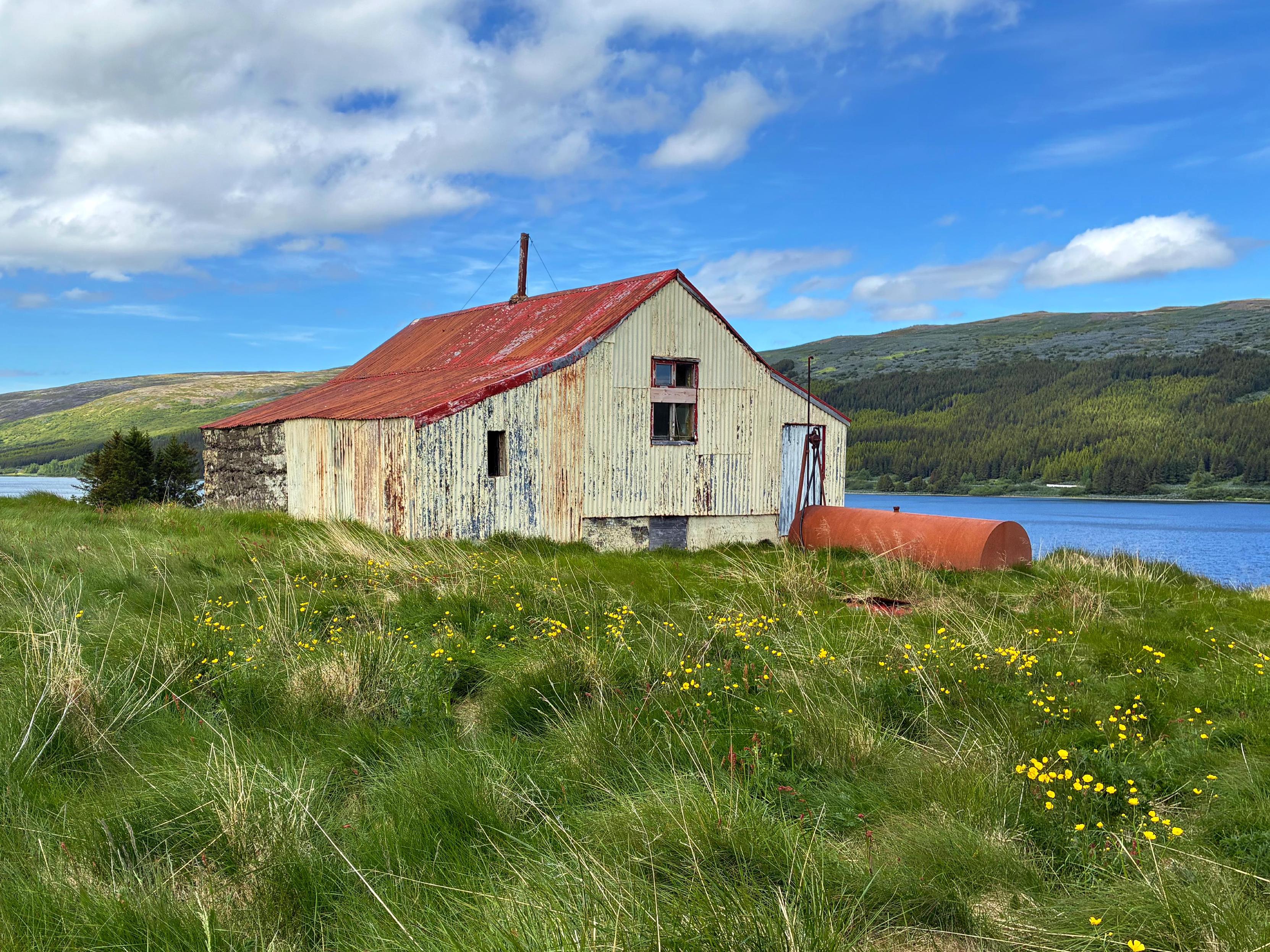 An abandoned farm with a mountain and a lake in the background.