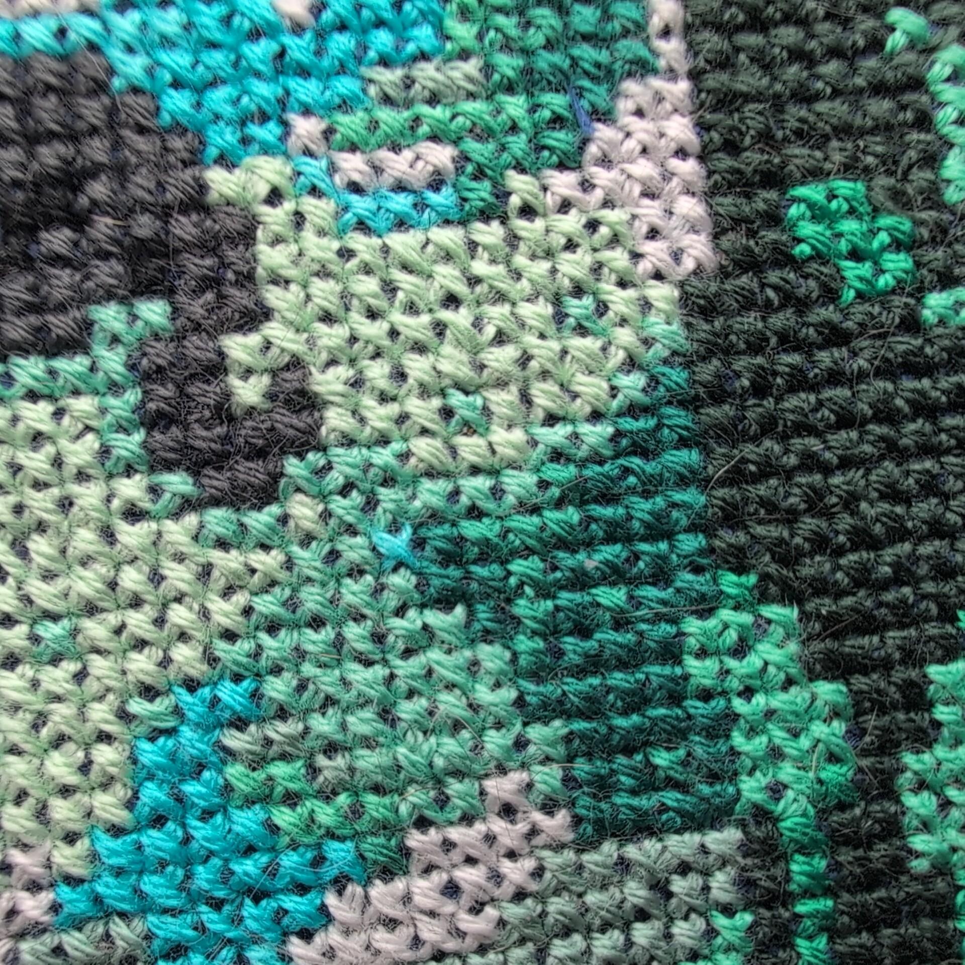 An extreme closeup of a cross stitch showing two animals's tails as they walk through a forest.