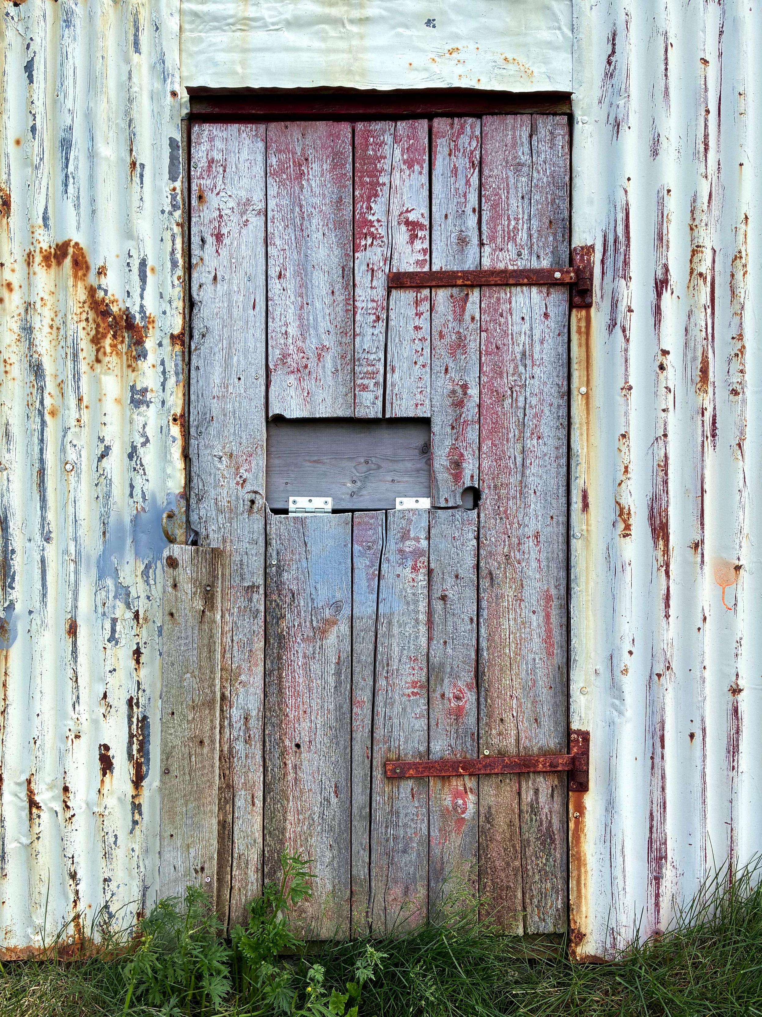 A weathered wood door with rusty hinges.