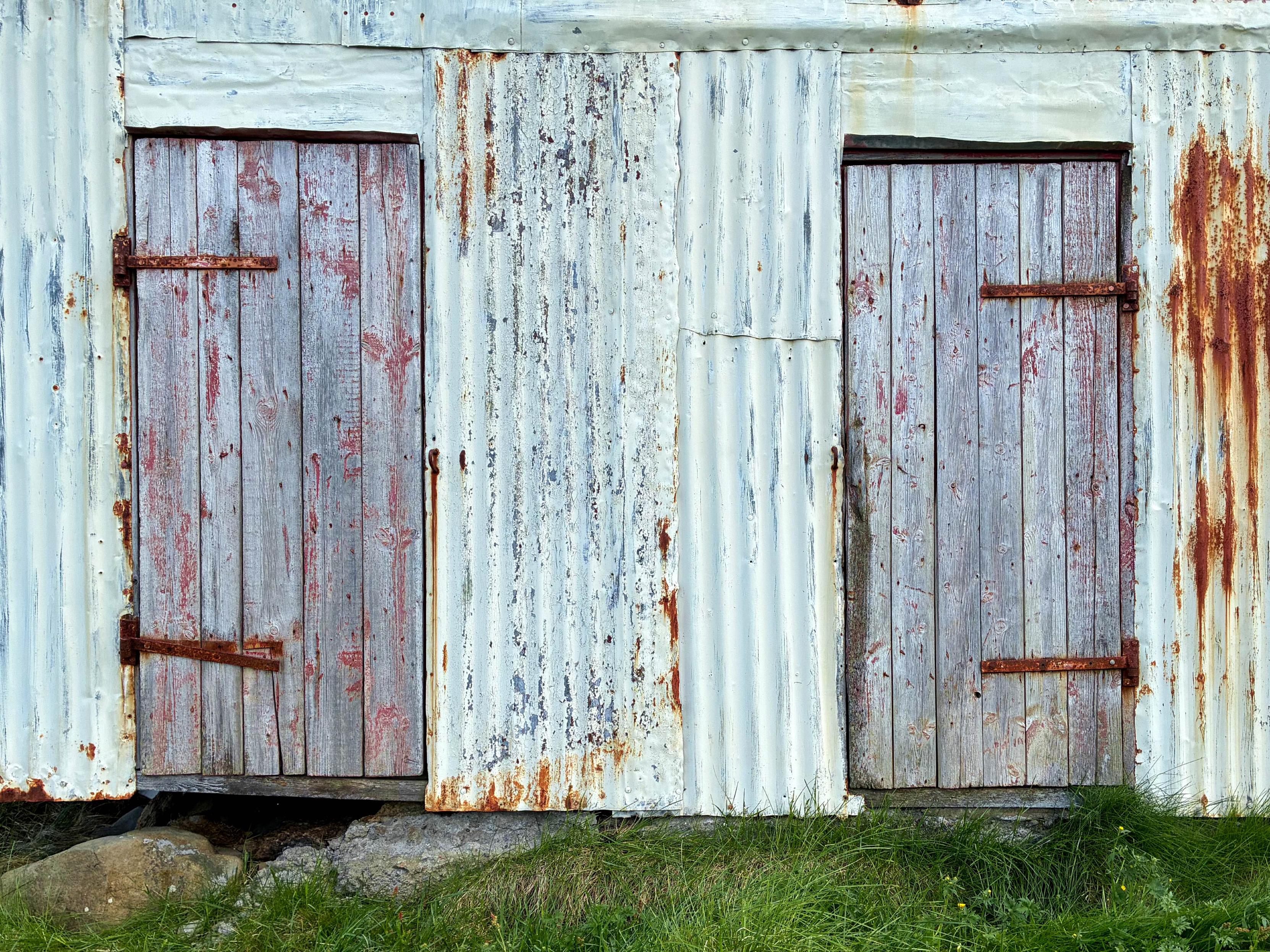 Two weathered wood doors with rusty hinges