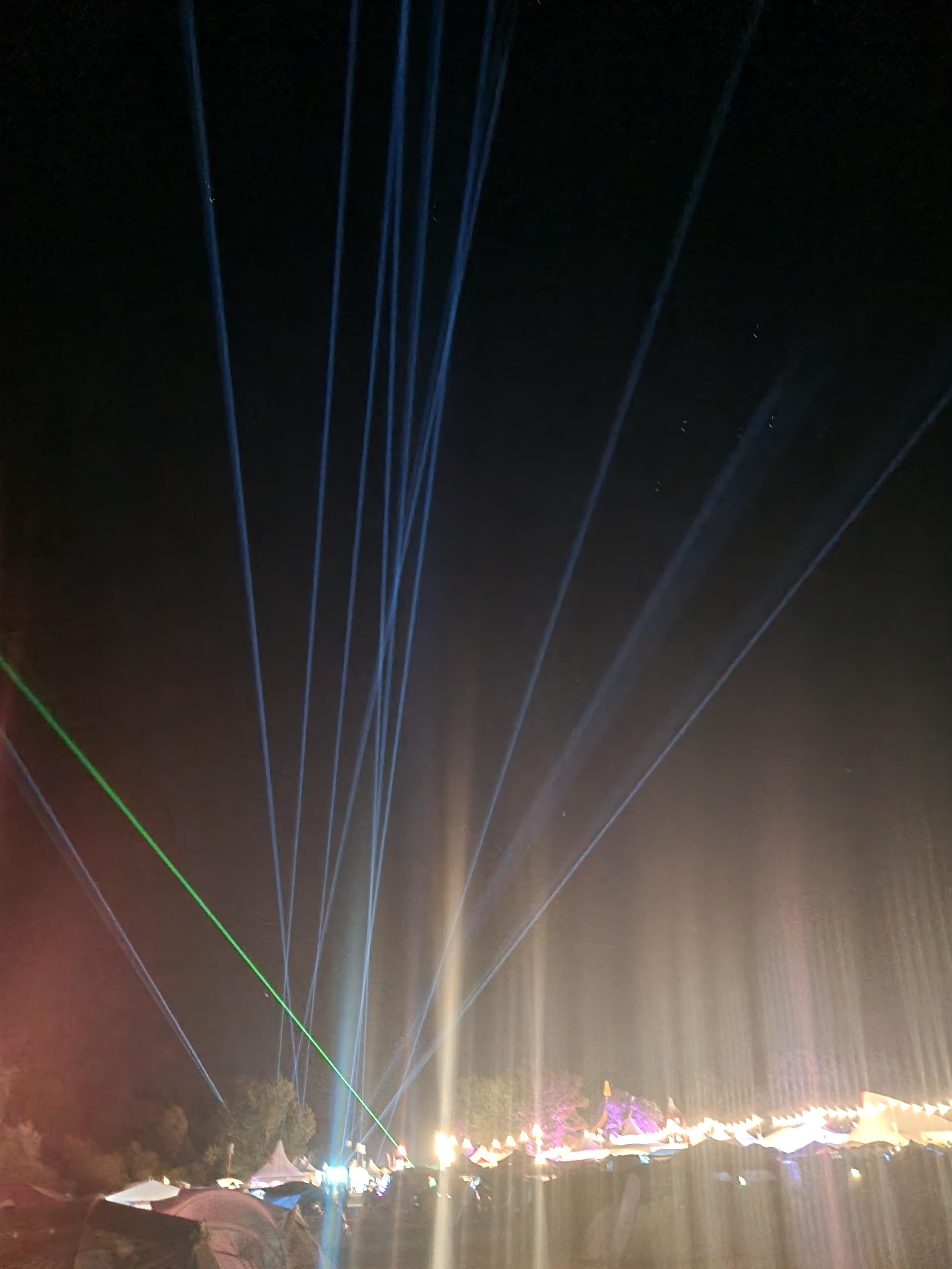 A night sky illuminated with lasers and bright camping lights