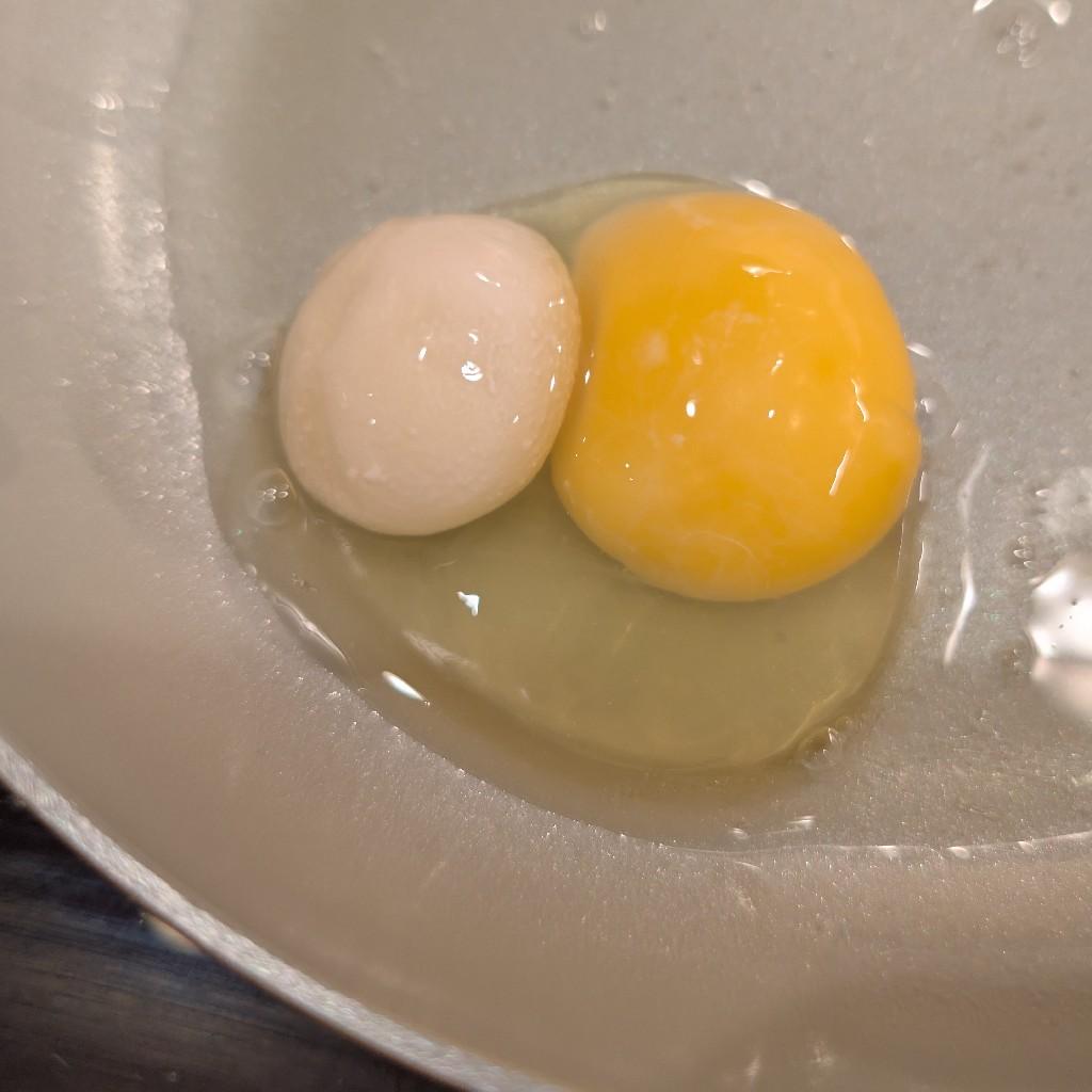 A chicken egg is cracked in a frying pan, with a yellow yolk surrounded by transparent whites, and another white mass slightly smaller than the yolk. (See next photo.)
